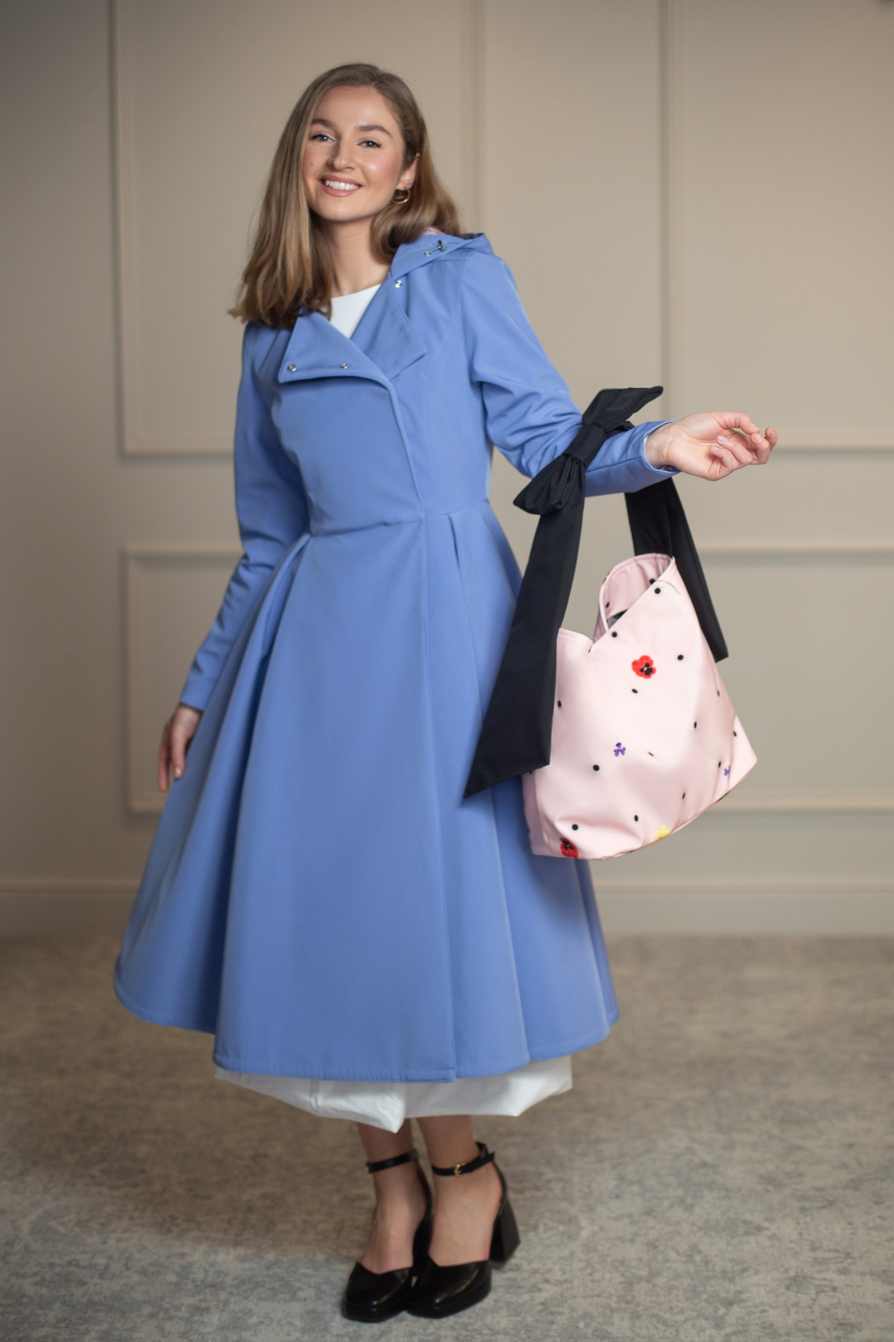 Pink Blossom tote bag with floral print, black polka dots, and bow detail, styled with Blue Breeze coat; perfect match for RainSisters outerwear.
