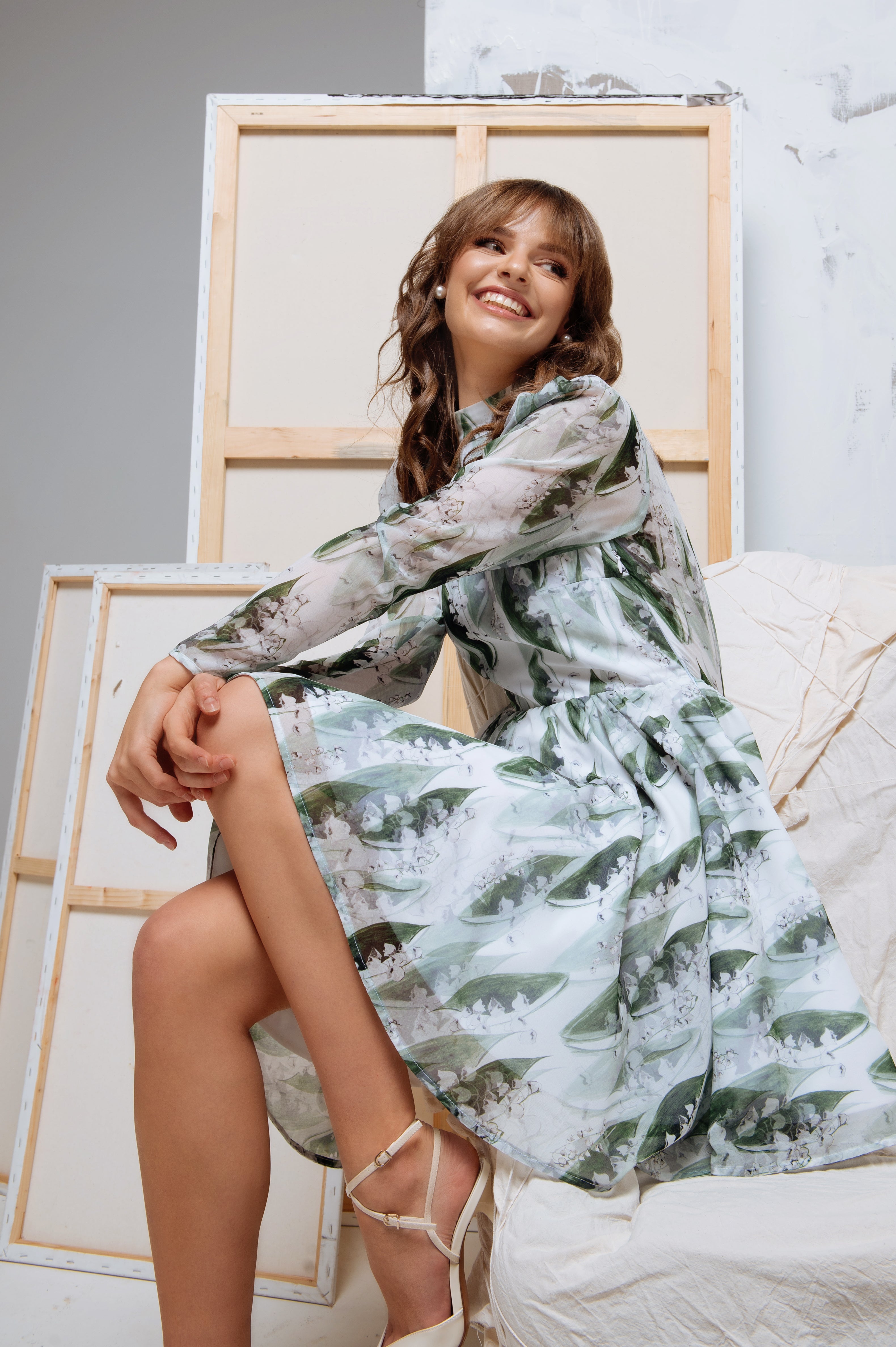 Model seated gracefully in the dress, with focus on the long sleeves and gathered shoulder details.