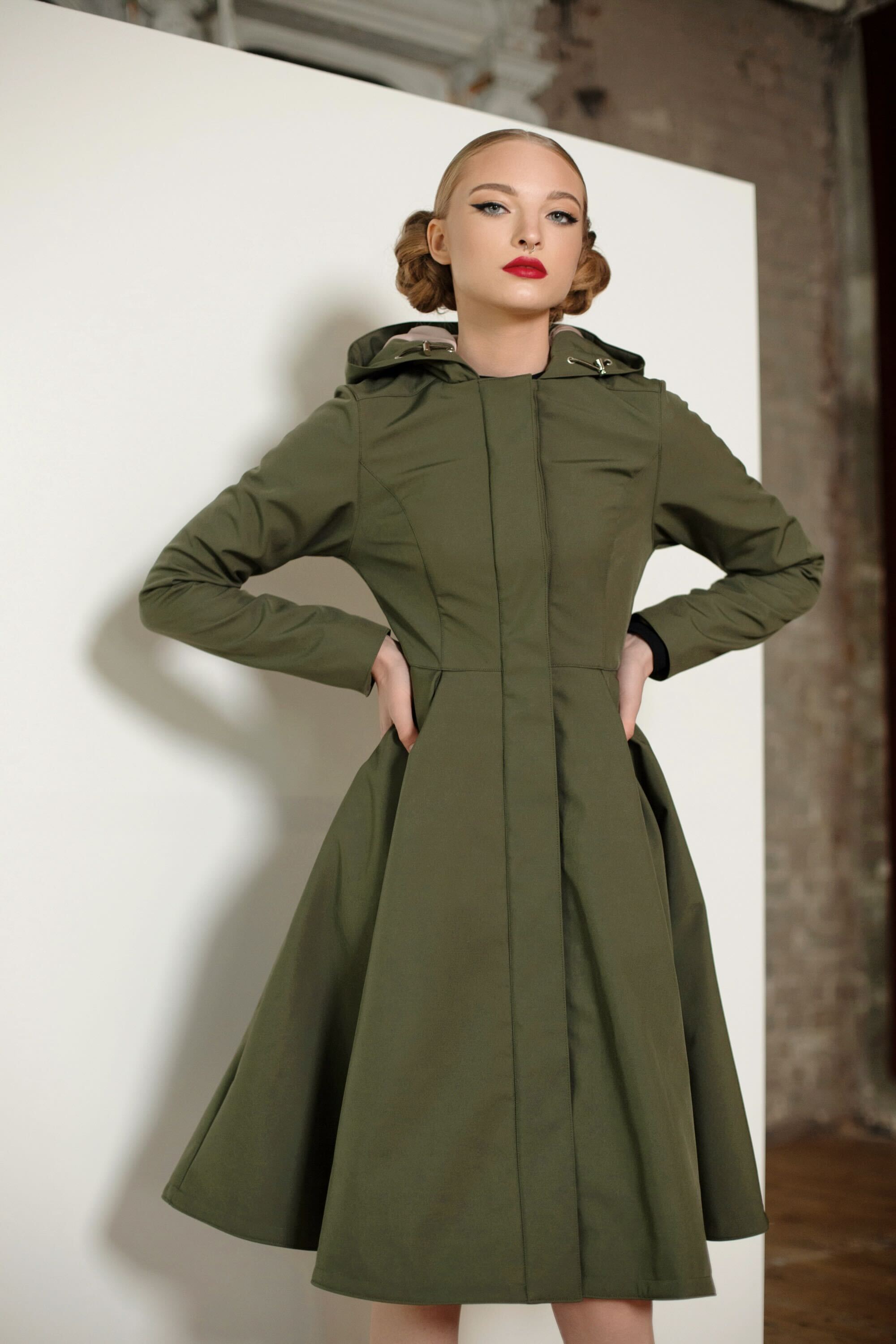Moss Green women’s coat by RainSisters with fitted upper body, flared pleated skirt, and snap button closure.