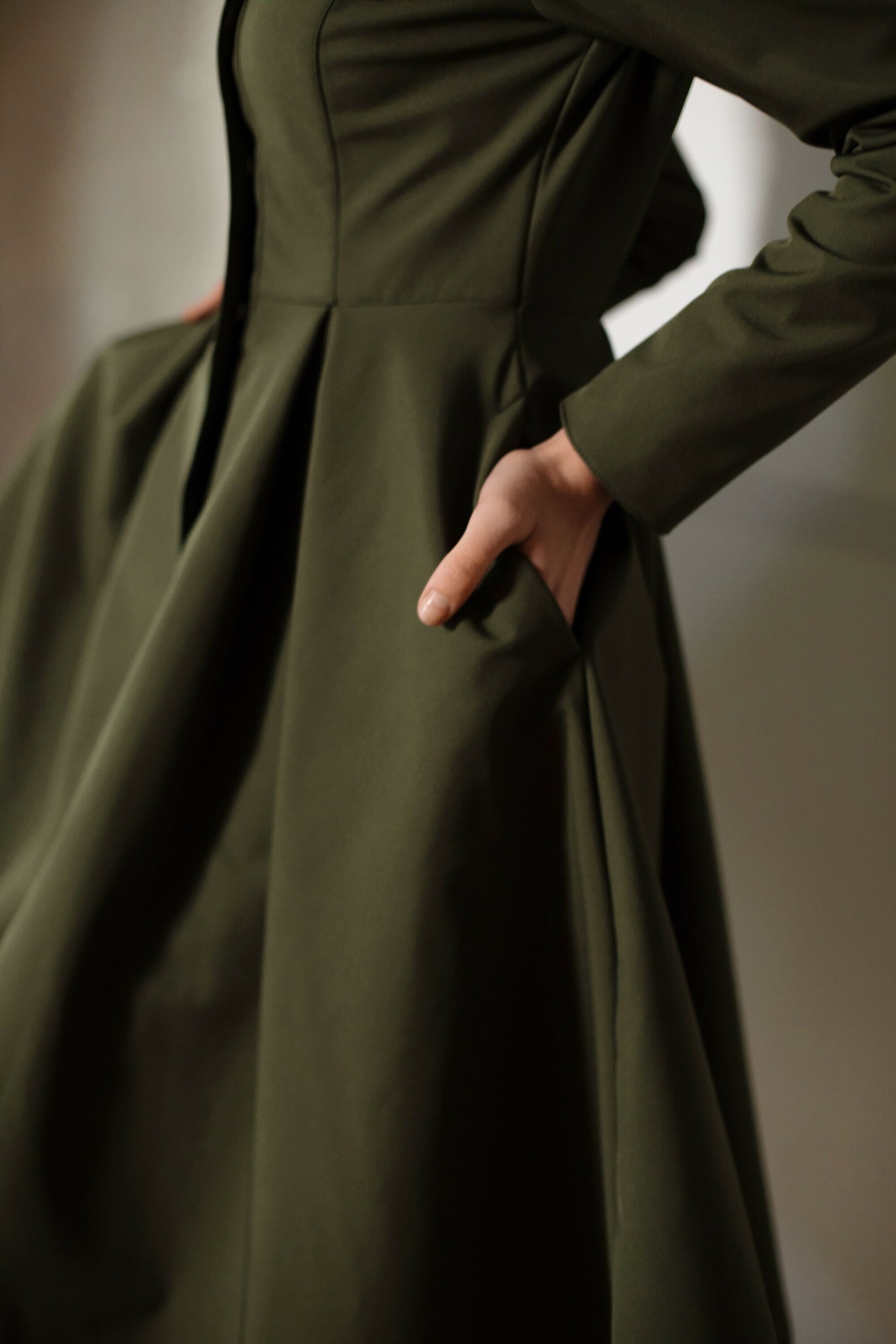 Elegant Moss Green women’s coat by RainSisters with fitted bodice, flared pleated skirt, and flattering feminine silhouette.