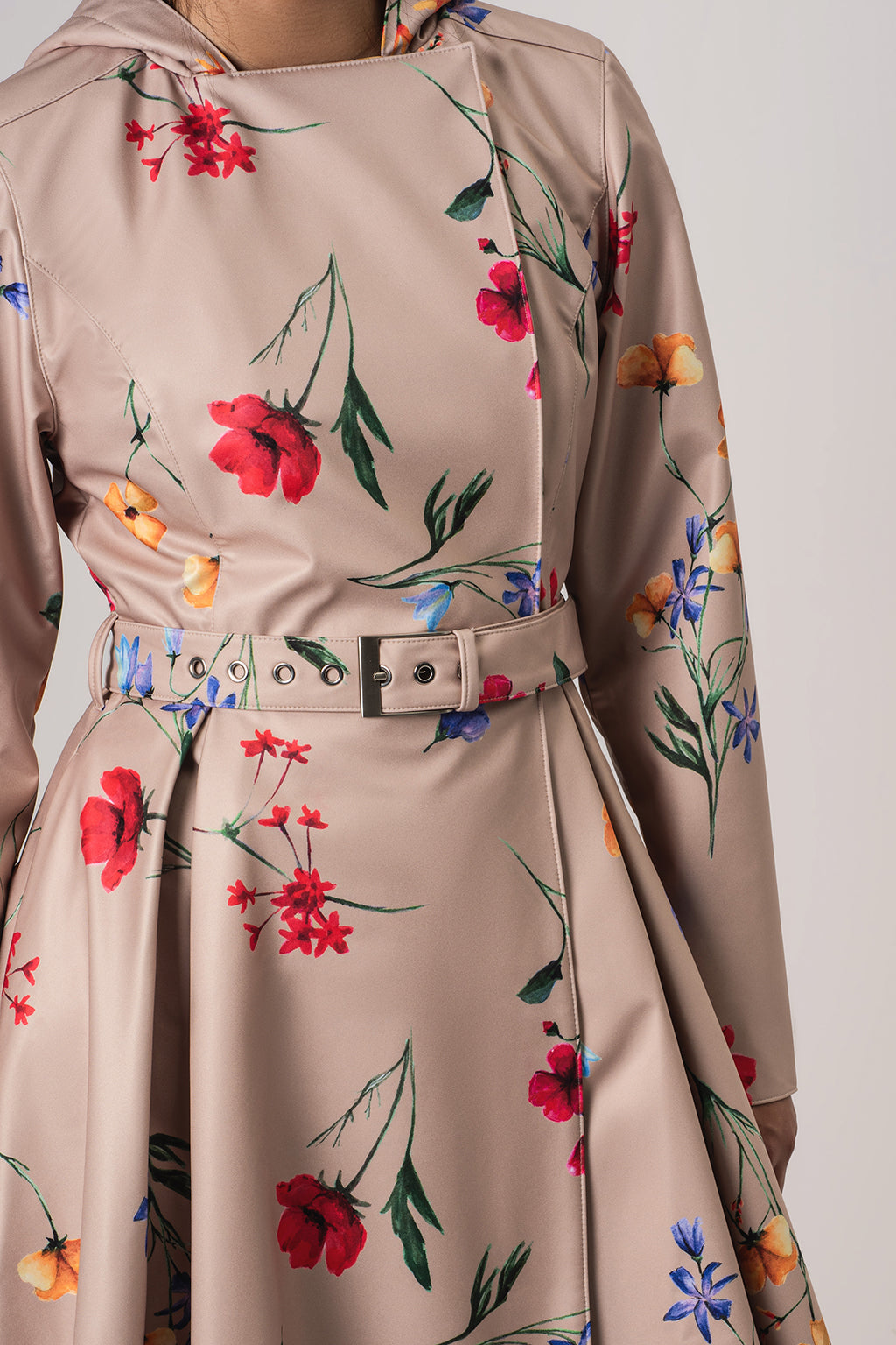 A close-up of RainSisters beige satin-like raincoat Spring Bloom with a colorful floral print, featuring a matching belt with silver-tone hardware.