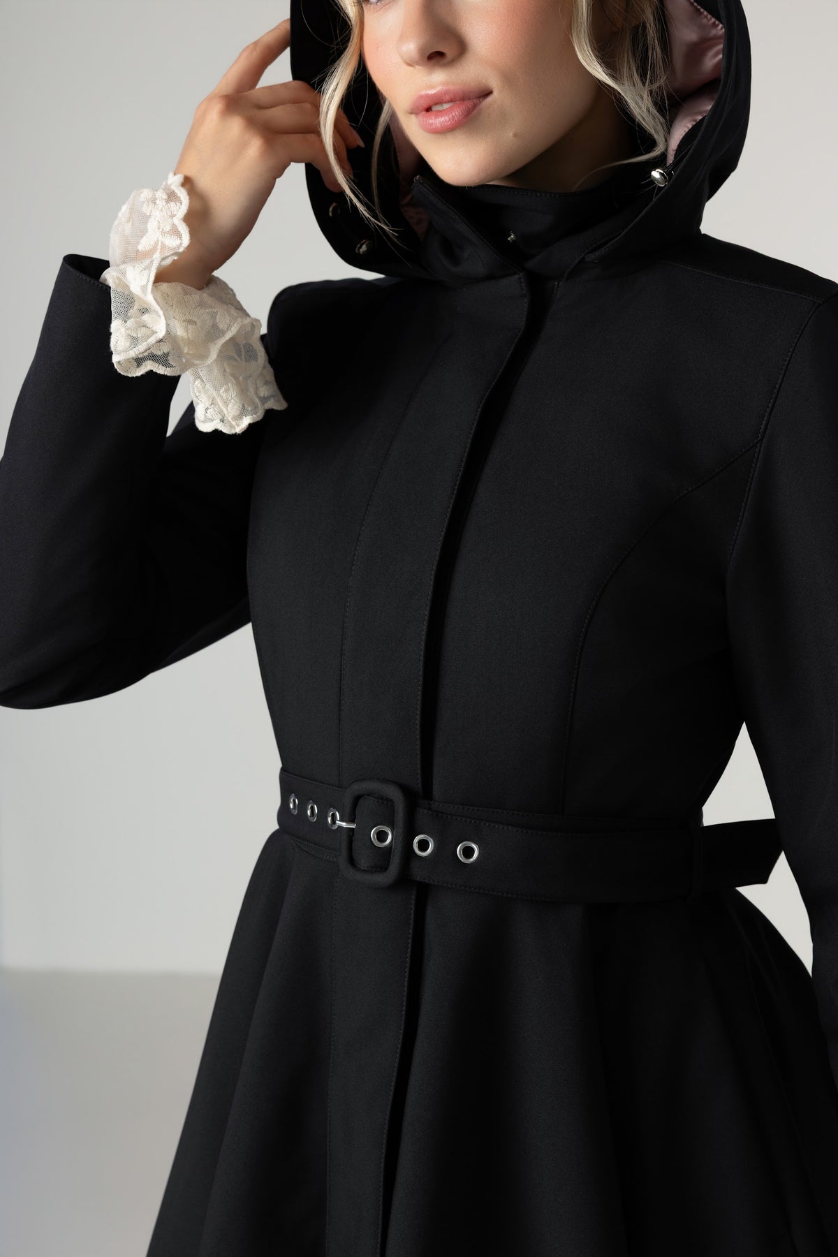 A model wears an elegant Rainsisters black belted winter coat with a fitted waist and full-circle skirt.