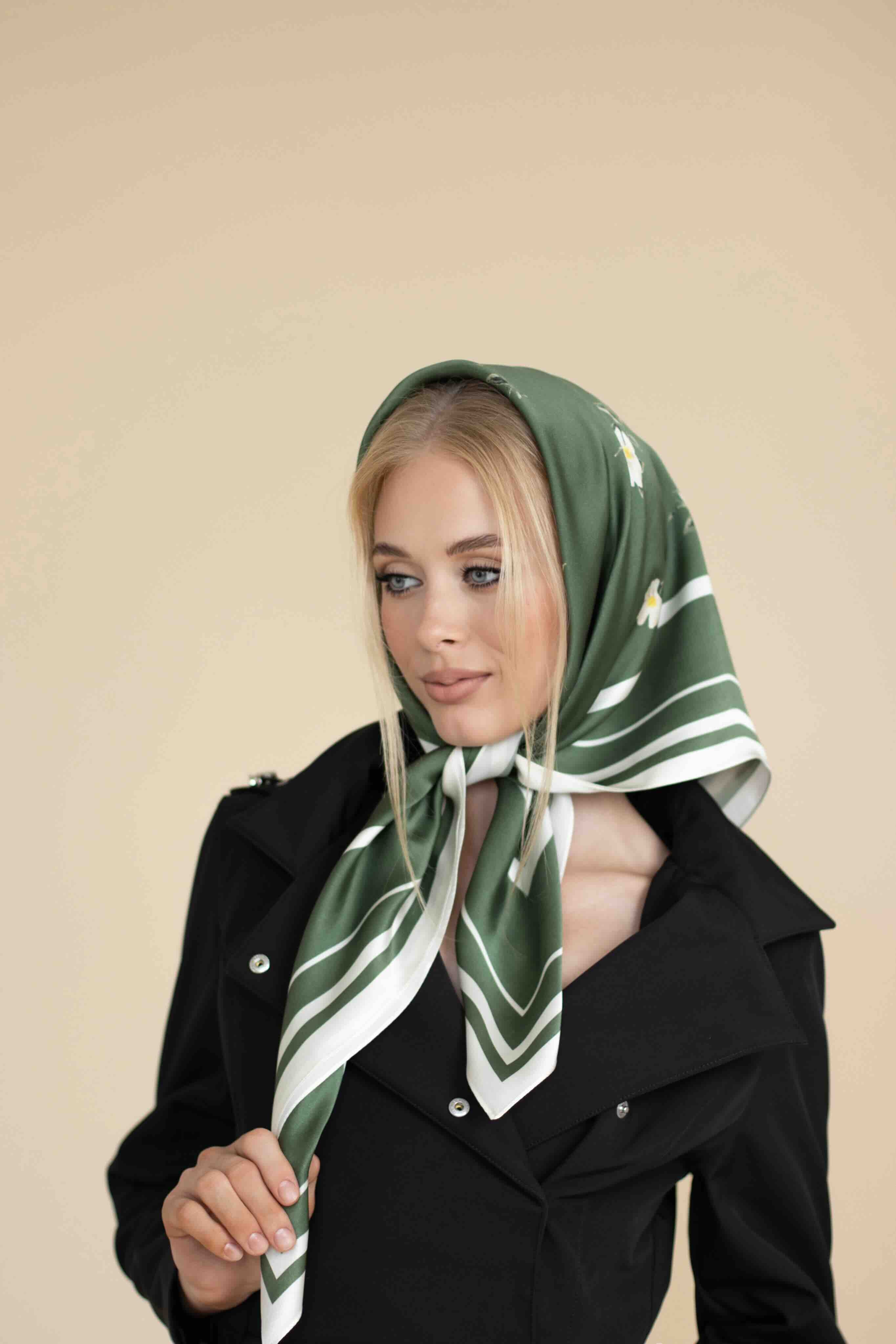 Woman wearing a green and white patterned scarf on a beige background