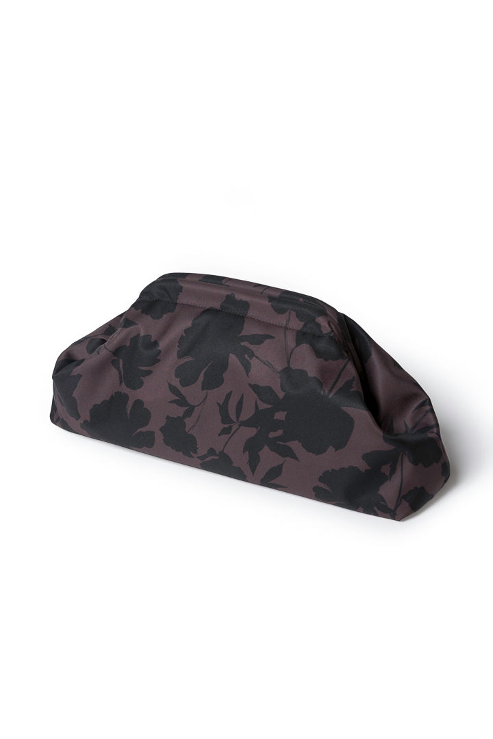 A dark brown and black floral patterned clutch bag, photographed from an angle on a clean white background.