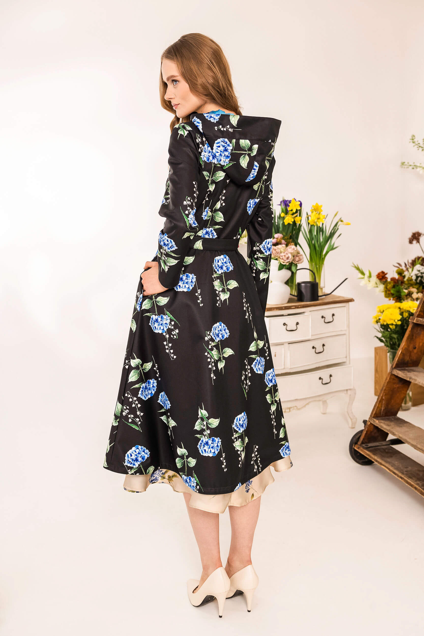 Back view of black floral coat with adjustable hood and flowing silhouette