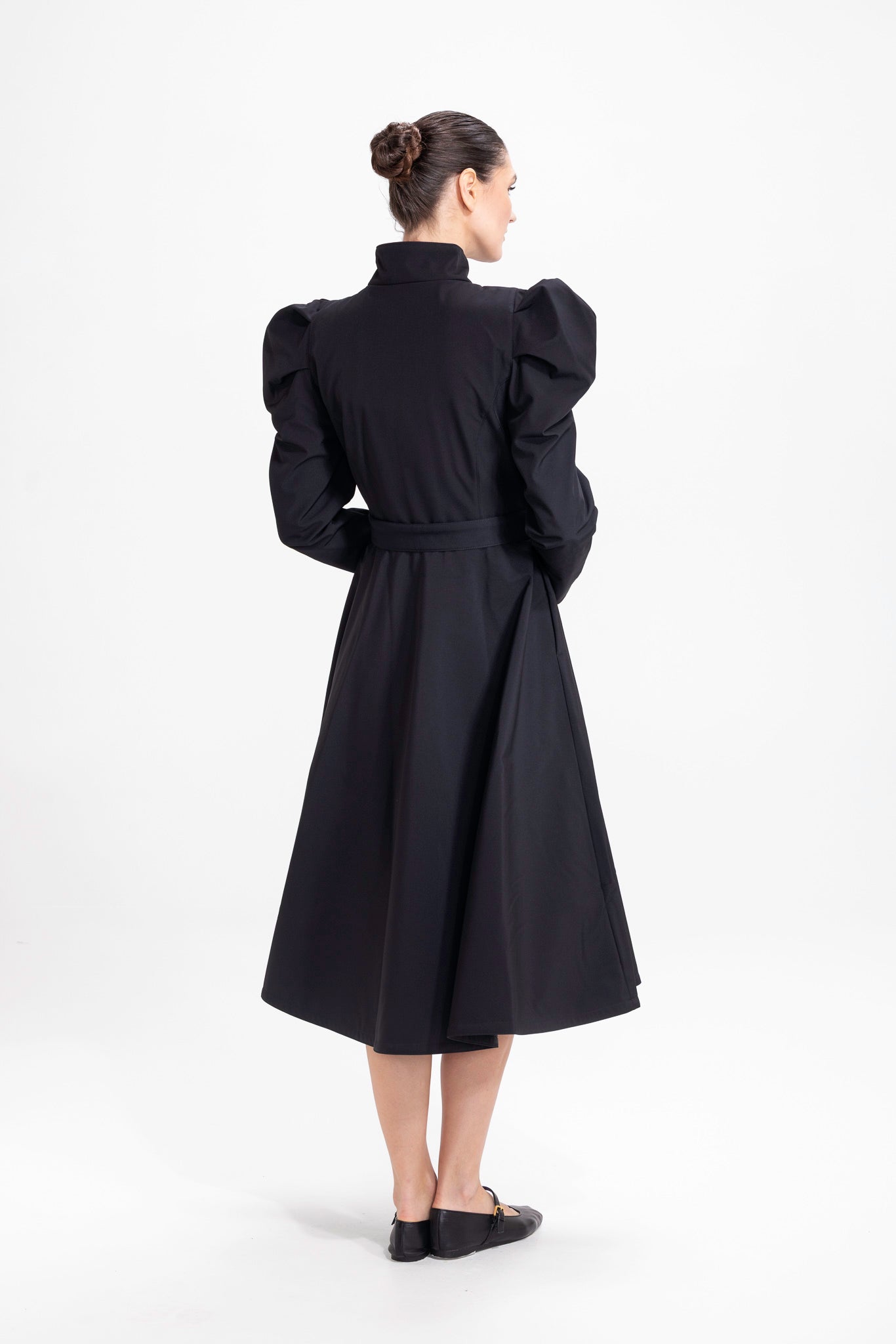 Back view of black women's coat with voluminous skirt and tailored waist fit