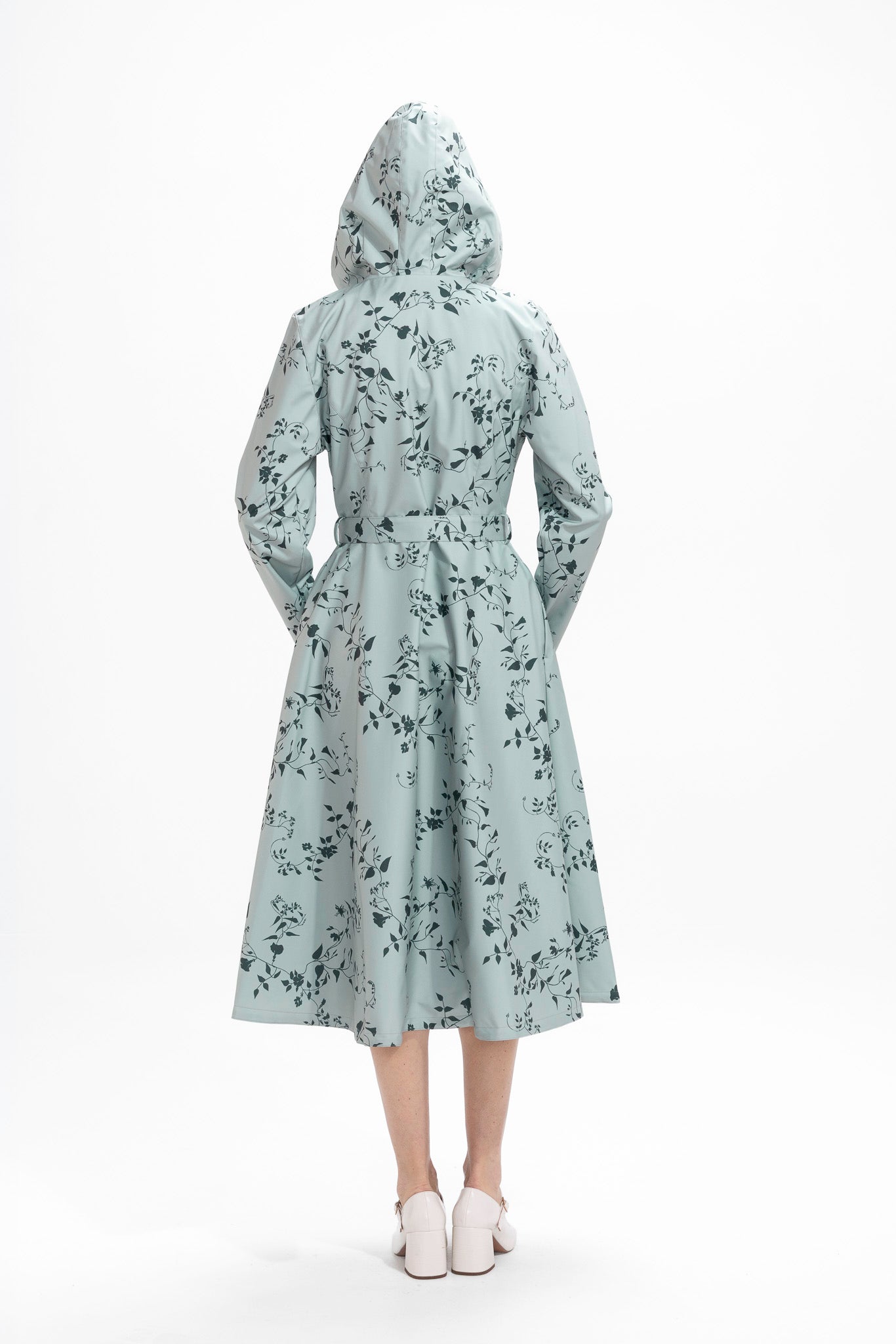 Back view of mint green women's trench coat with dark green floral pattern and tailored fit