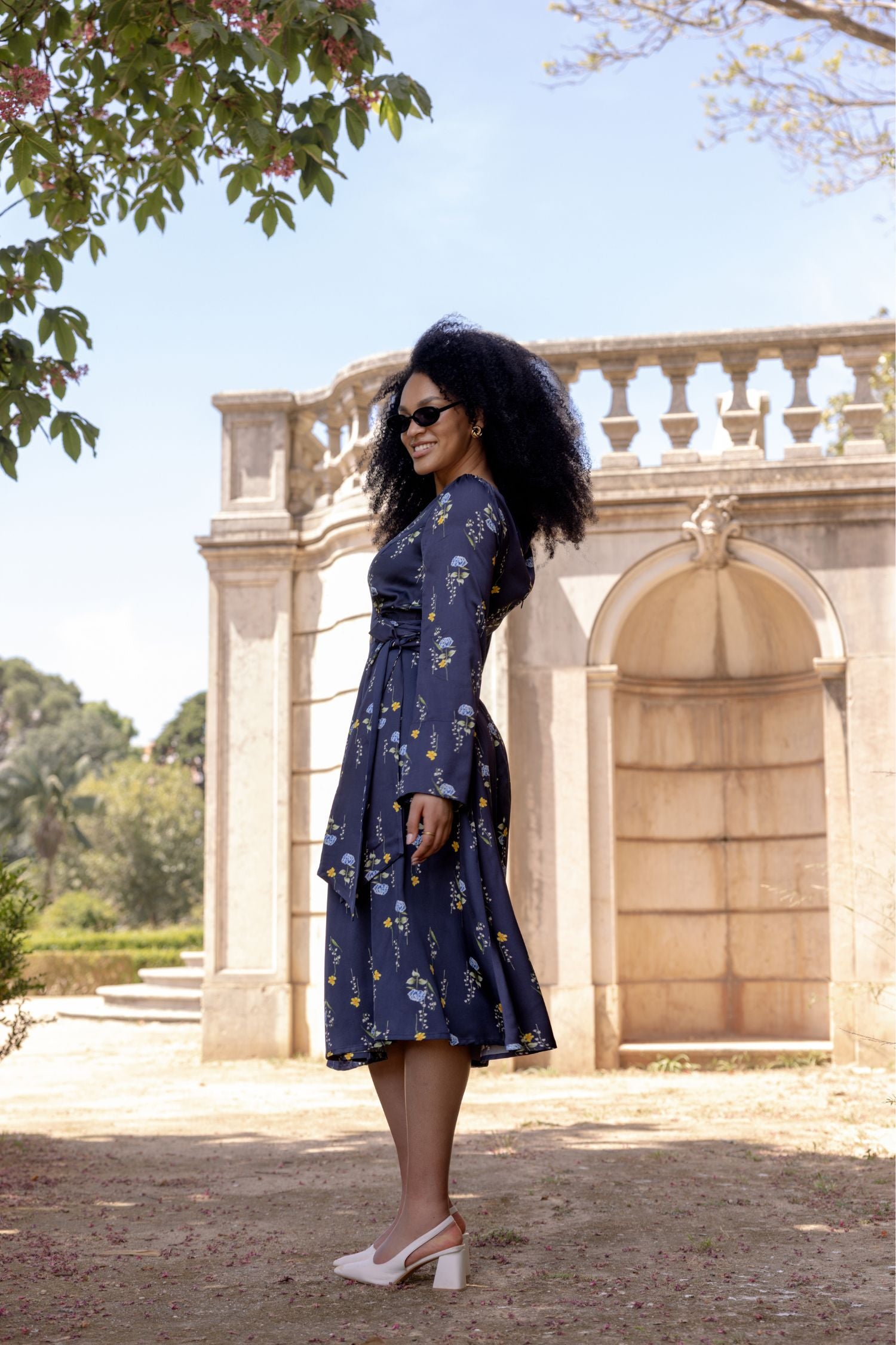 Woman wearing the Meadow Dream midi dress with soft flowing skirt, open shoulder detail, and long sleeves