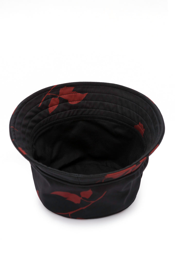 A black bucket hat with a red leaf pattern, photographed from a top-down angle on a white background.