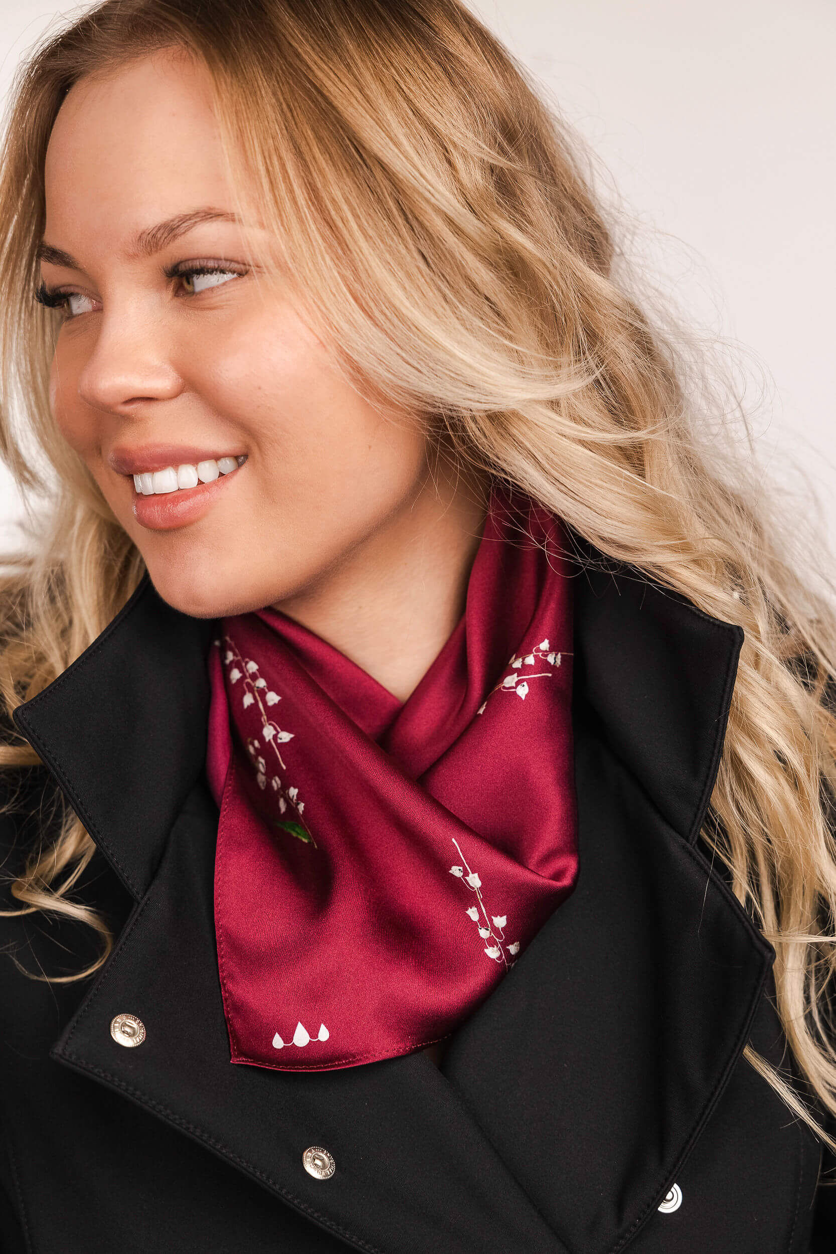 Woman wearing a red scarf with white patterns and a black coat.