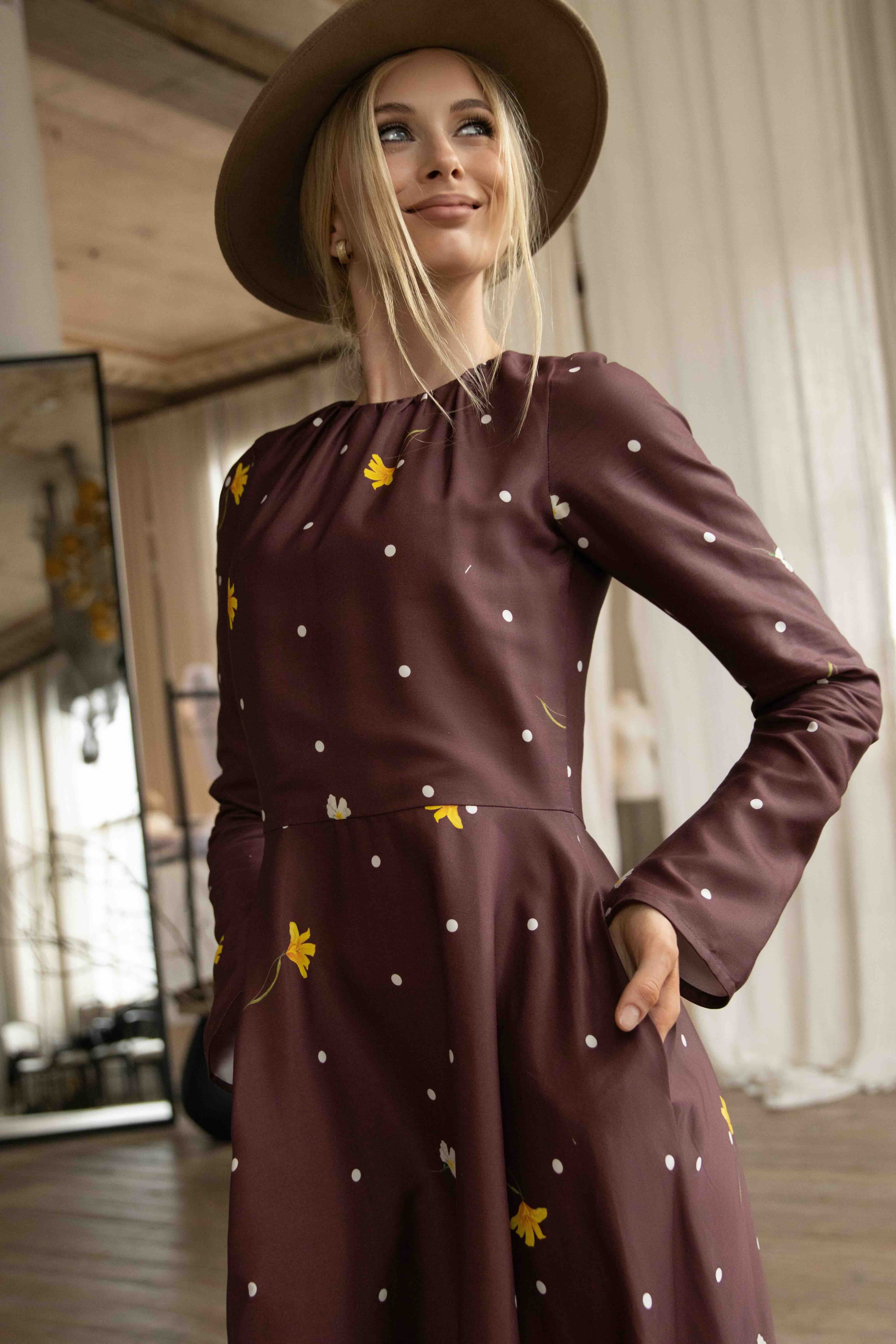 Romantic brown midi dress with floral and polka dot pattern, softly gathered neckline, and long flared sleeves.