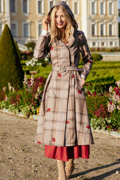 Woman in a plaid coat with red accents standing in a garden.