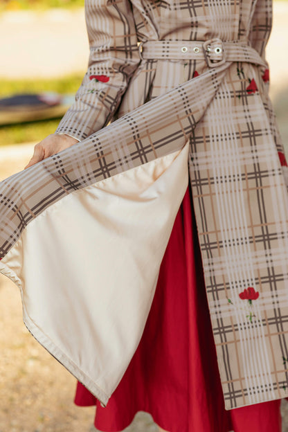 Model wearing a plaid coat with a belt, and red skirt outdoors.
