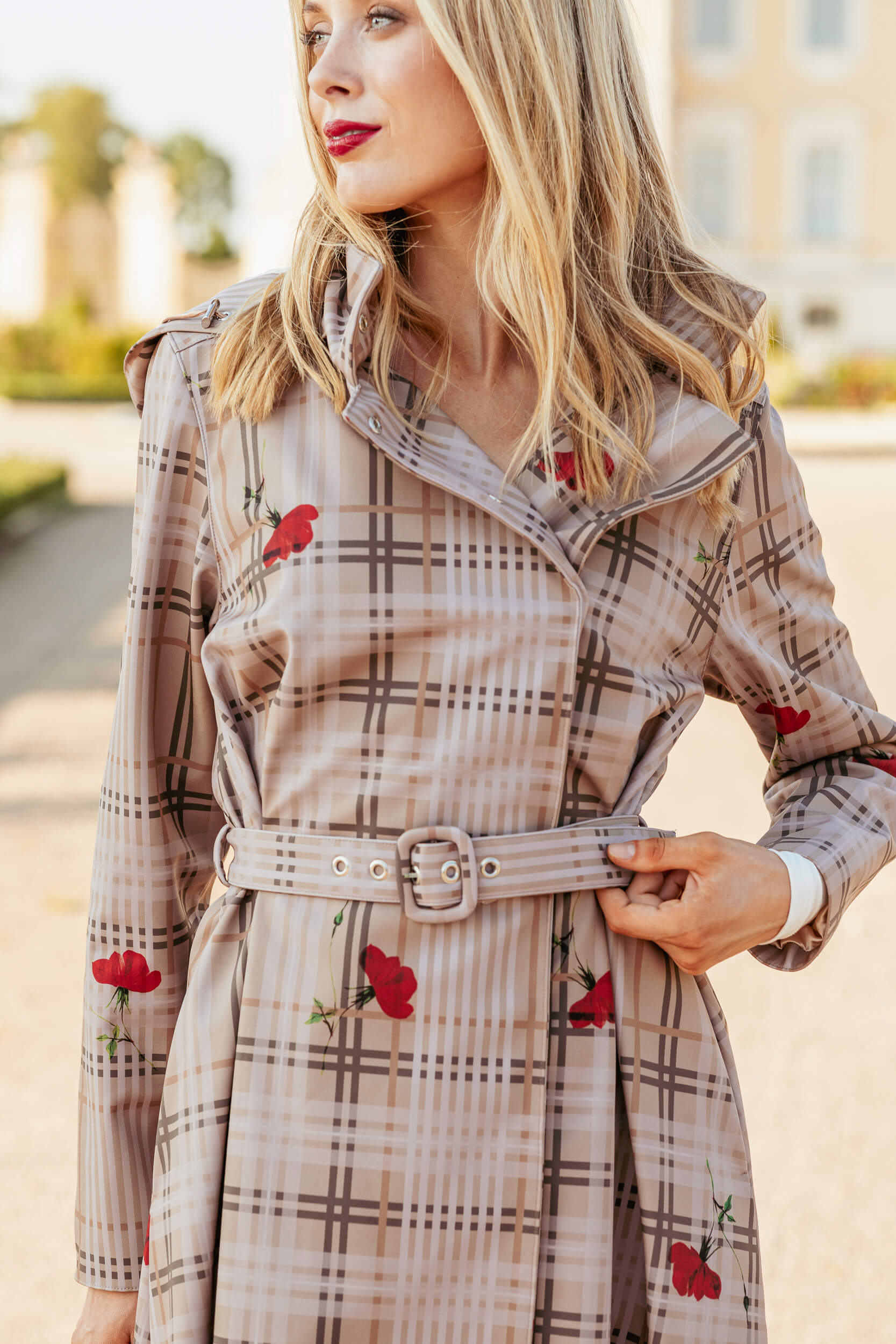 Woman wearing a plaid coat named Blush of the Crown with red flower accents outdoors.