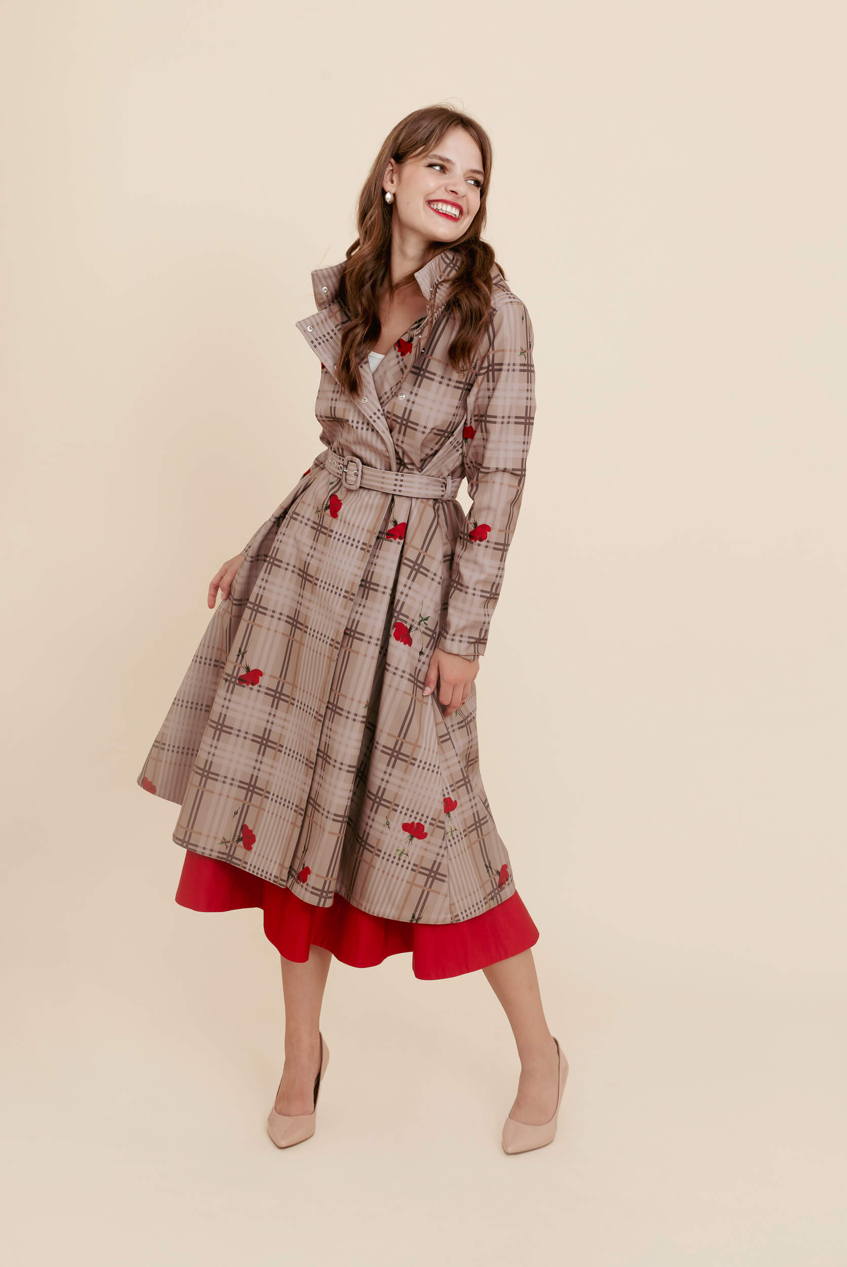 Woman wearing a plaid pattern coat with red accents on a beige background