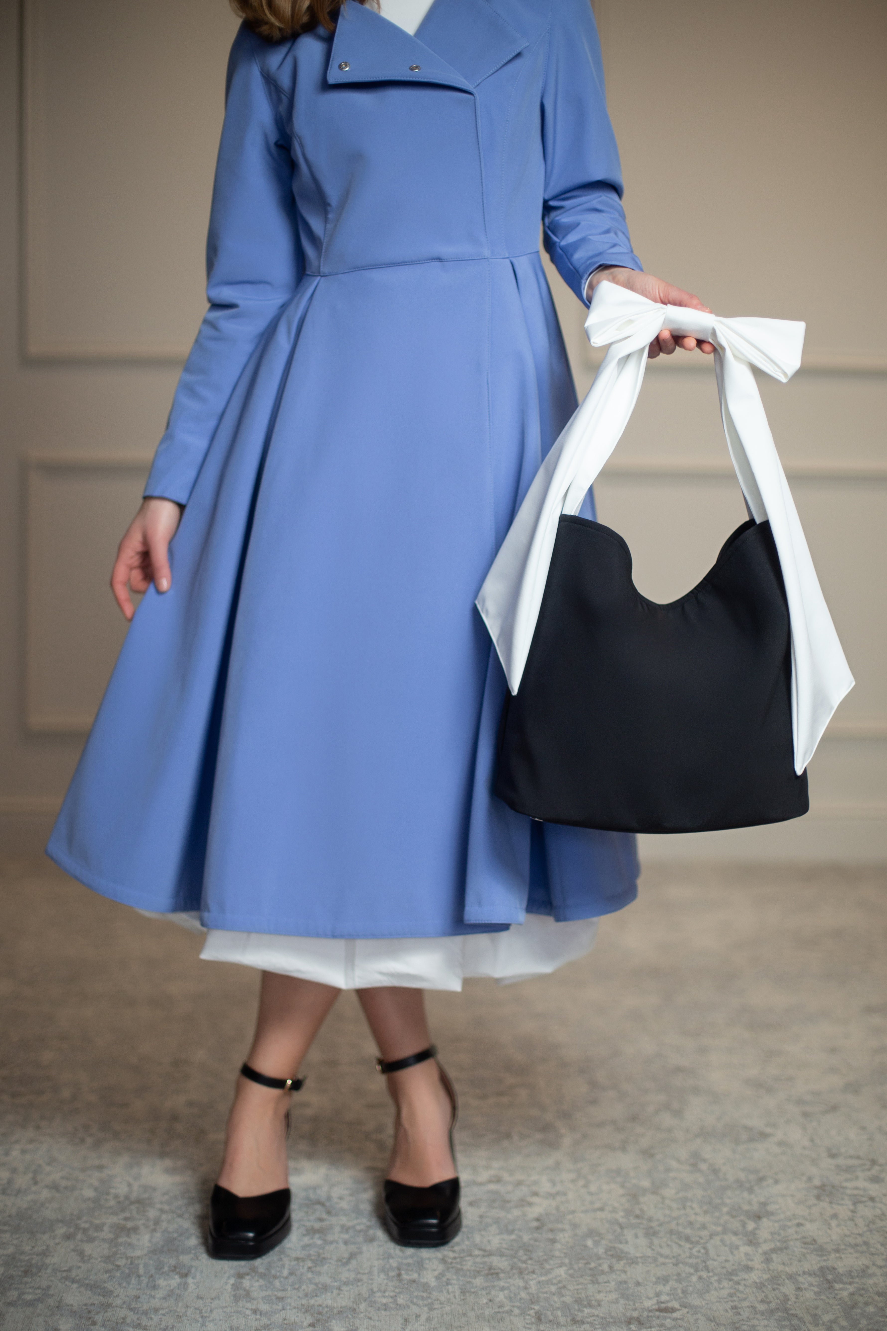 Water-resistant black tote with firm interior lining, stainless steel feet, and delicate bow accent—where functionality meets timeless style.