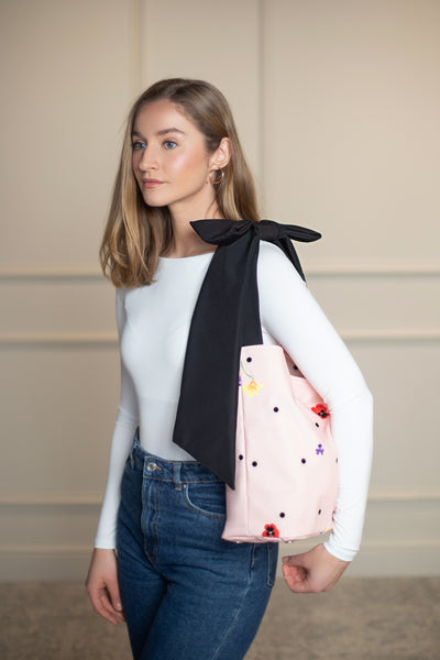 Chic pink floral tote featuring a mix of lilac, yellow, and red flowers, black dots, and an elegant bow—adds a whimsical touch to any outfit.