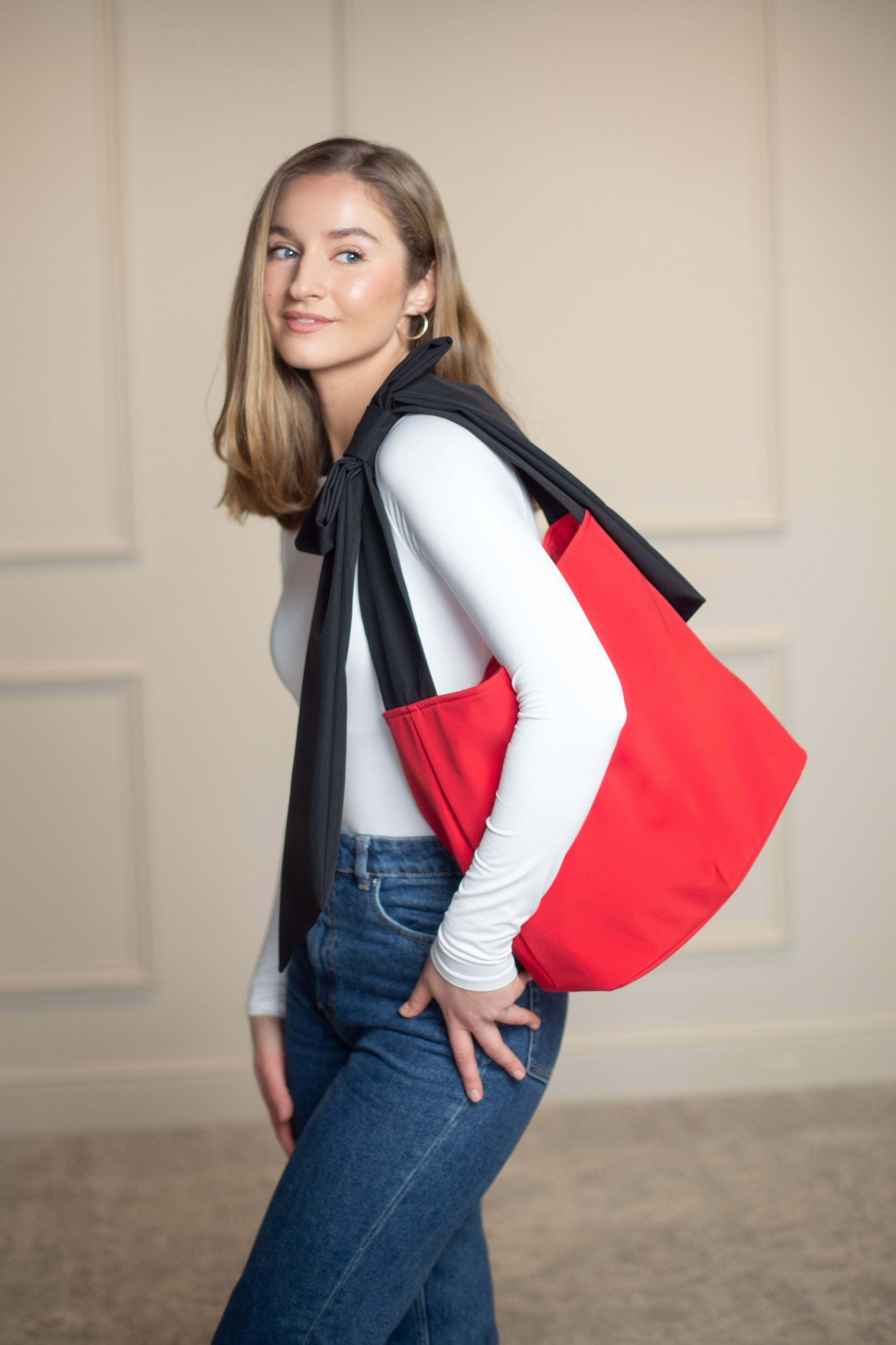 Water-resistant red tote with reinforced interior and stainless steel feet, combining style and structure for daily use.