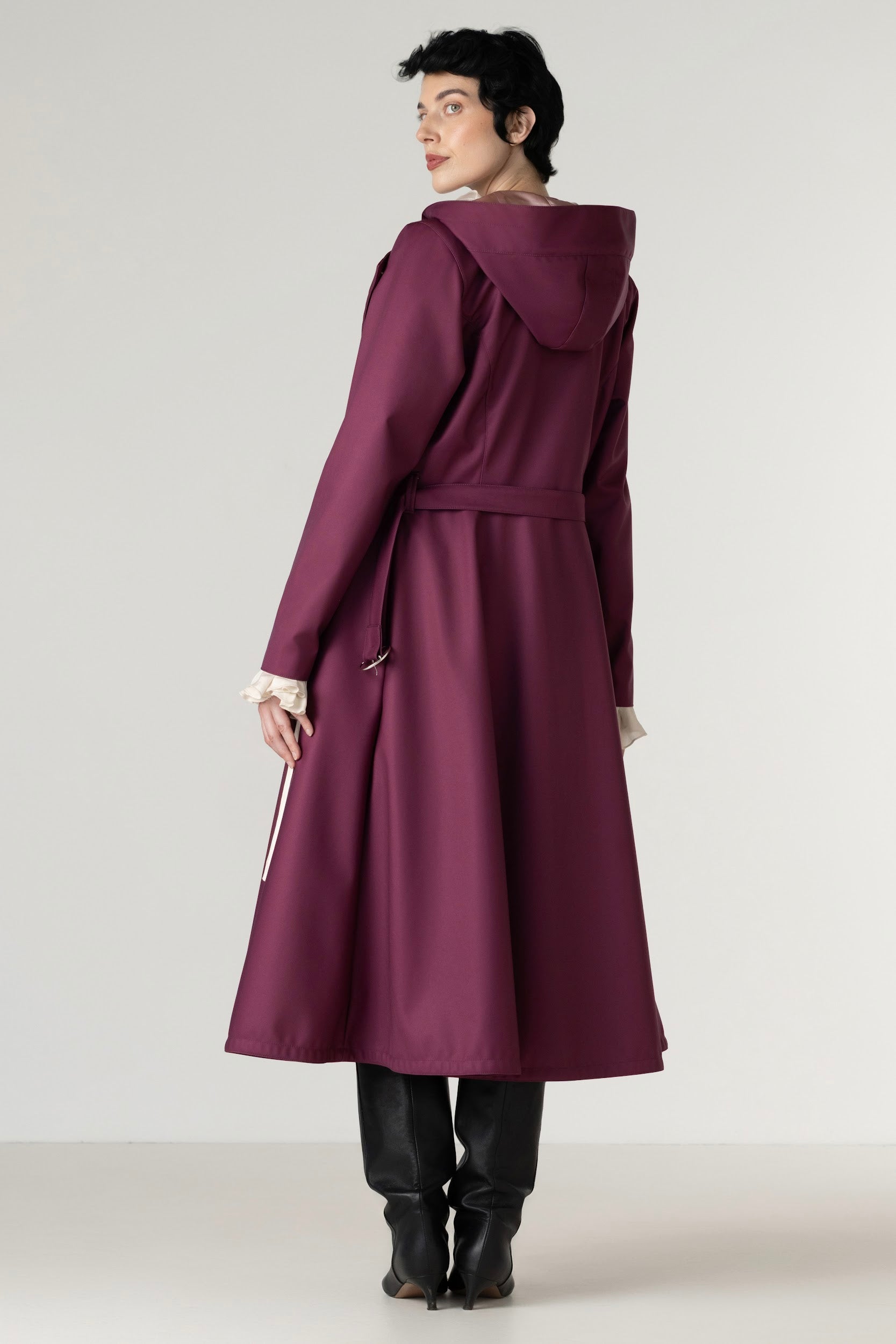Full-length view of a women's berry double-breasted trench coat with a removable hood and elegant tailored silhouette.
