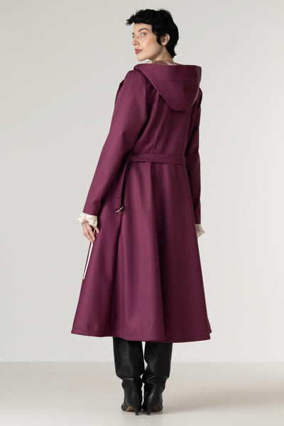Full-length view of a women's berry double-breasted trench coat with a removable hood and elegant tailored silhouette.