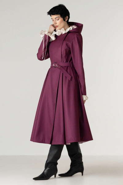 Full-length view of a women's deep burgundy double-breasted trench coat with a matching buckle belt and tailored silhouette.