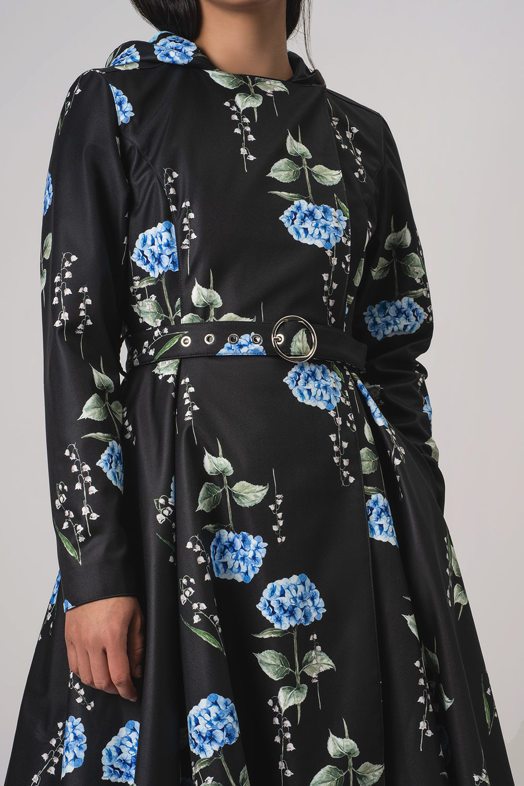 RainSisters black long-sleeve coat Flower Moon with a blue and green floral print, featuring a matching belt with silver hardware, shown on a model against a light gray background.