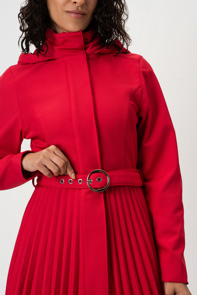 A close-up of a model wearing RainSisters bright red hooded coat Scarlet Waltz with a matching pleated skirt and a wide belt featuring a large round silver buckle.
