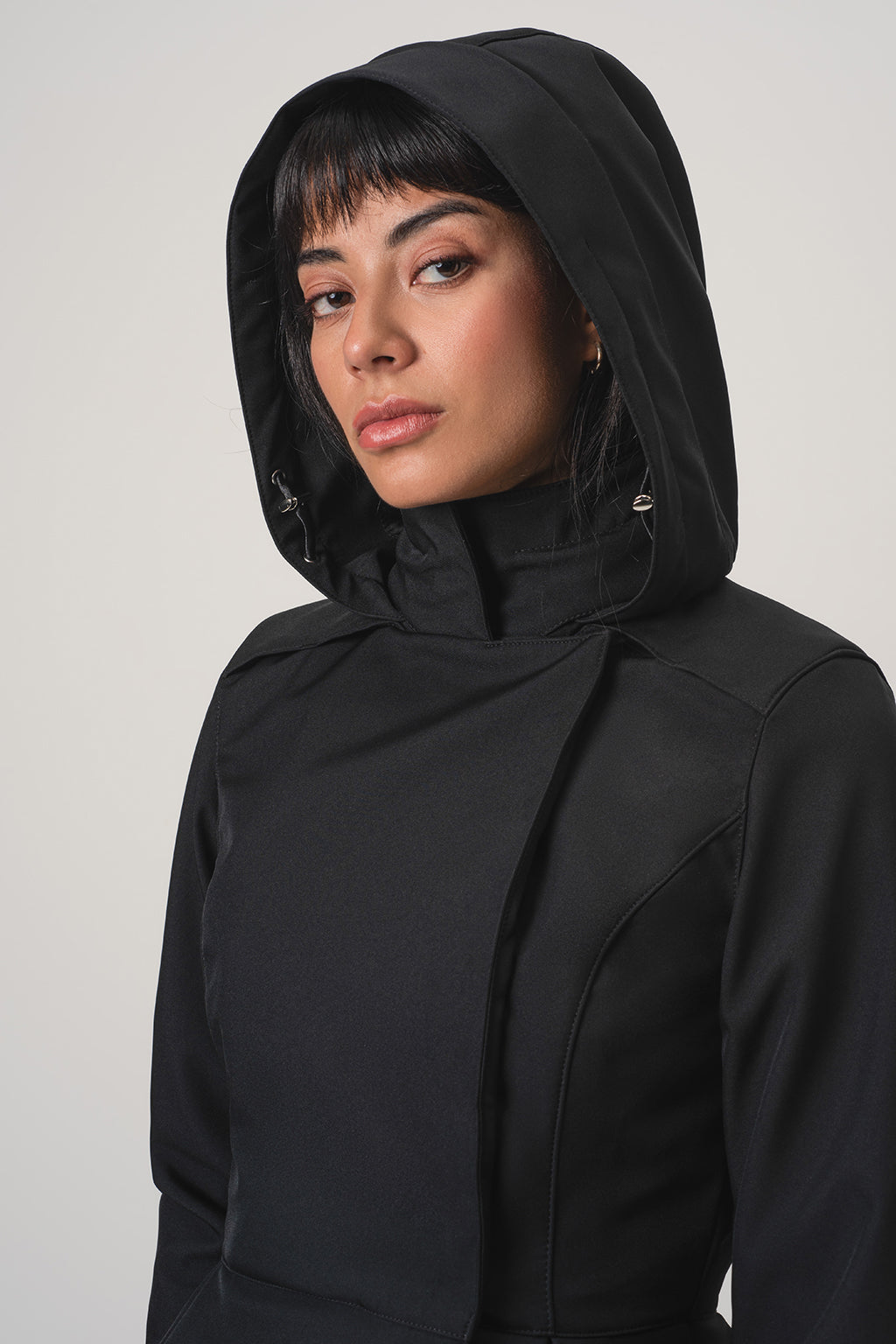 A close-up shot of a model wearing RainSisters black hooded jacket Moonlit Bow against a light gray studio background.