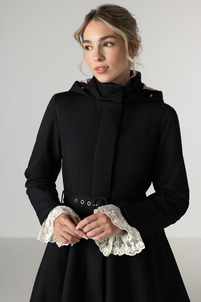 A model wears an elegant black fit-and-flare warm winter coat with a high neck and full-circle skirt.