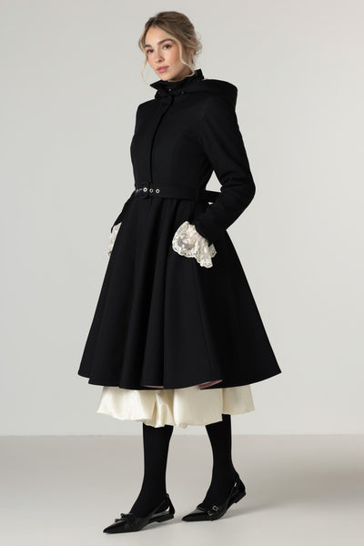 A model wears a black high-neck winter coat with a flared skirt and matching black belt.