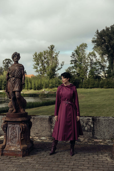 Women's berry double-breasted trench coat photographed outdoors, showcasing its elegant silhouette.