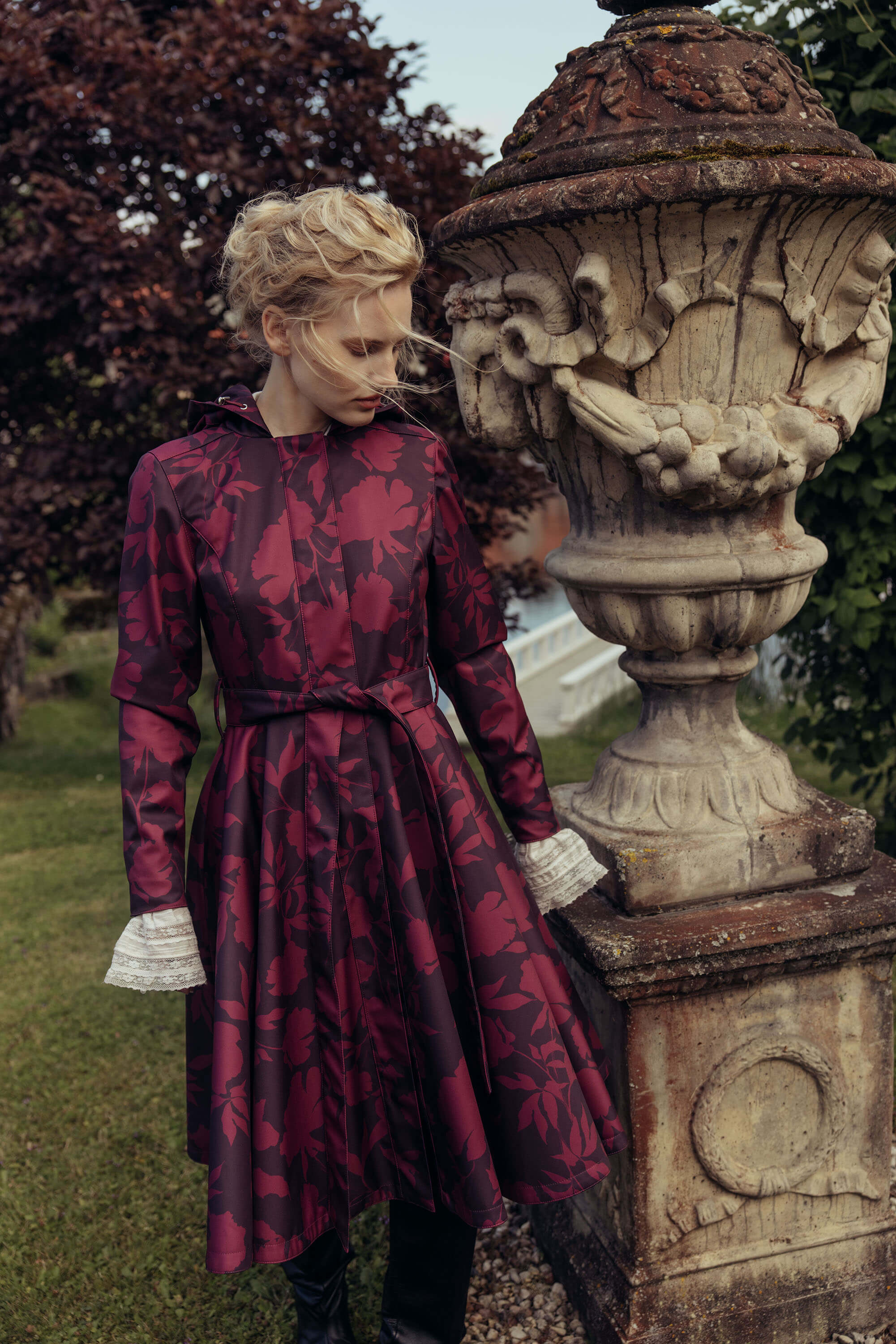 Women's burgundy floral coat with a flowing full circle skirt captured outdoors, showcasing its feminine silhouette in motion.