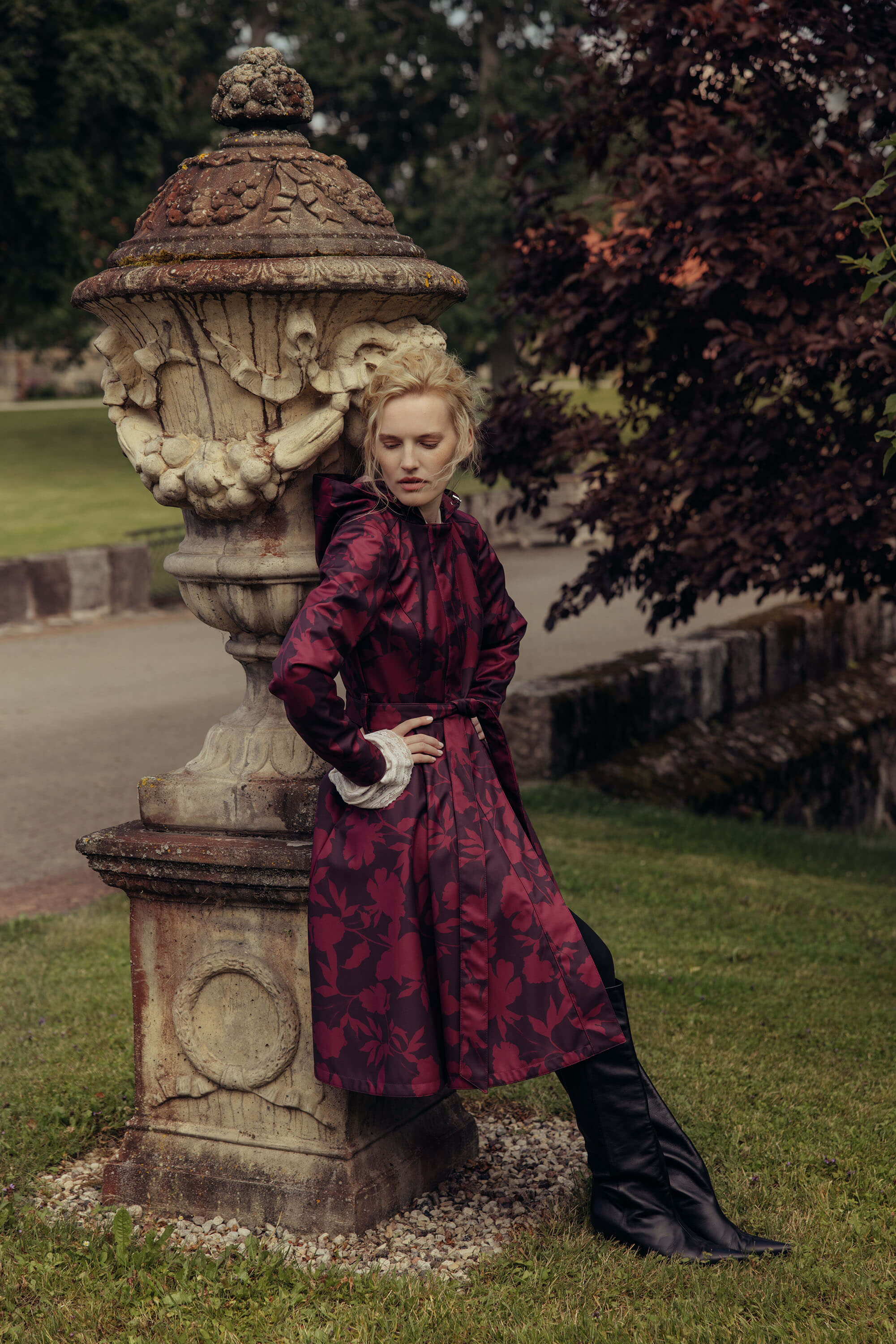 Woman wearing a burgundy floral fit and flare coat with a full circle skirt styled outdoors in an elegant autumn setting.