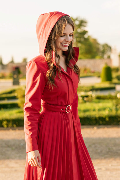 Woman wearing a red coat with a hood in an outdoor setting.
