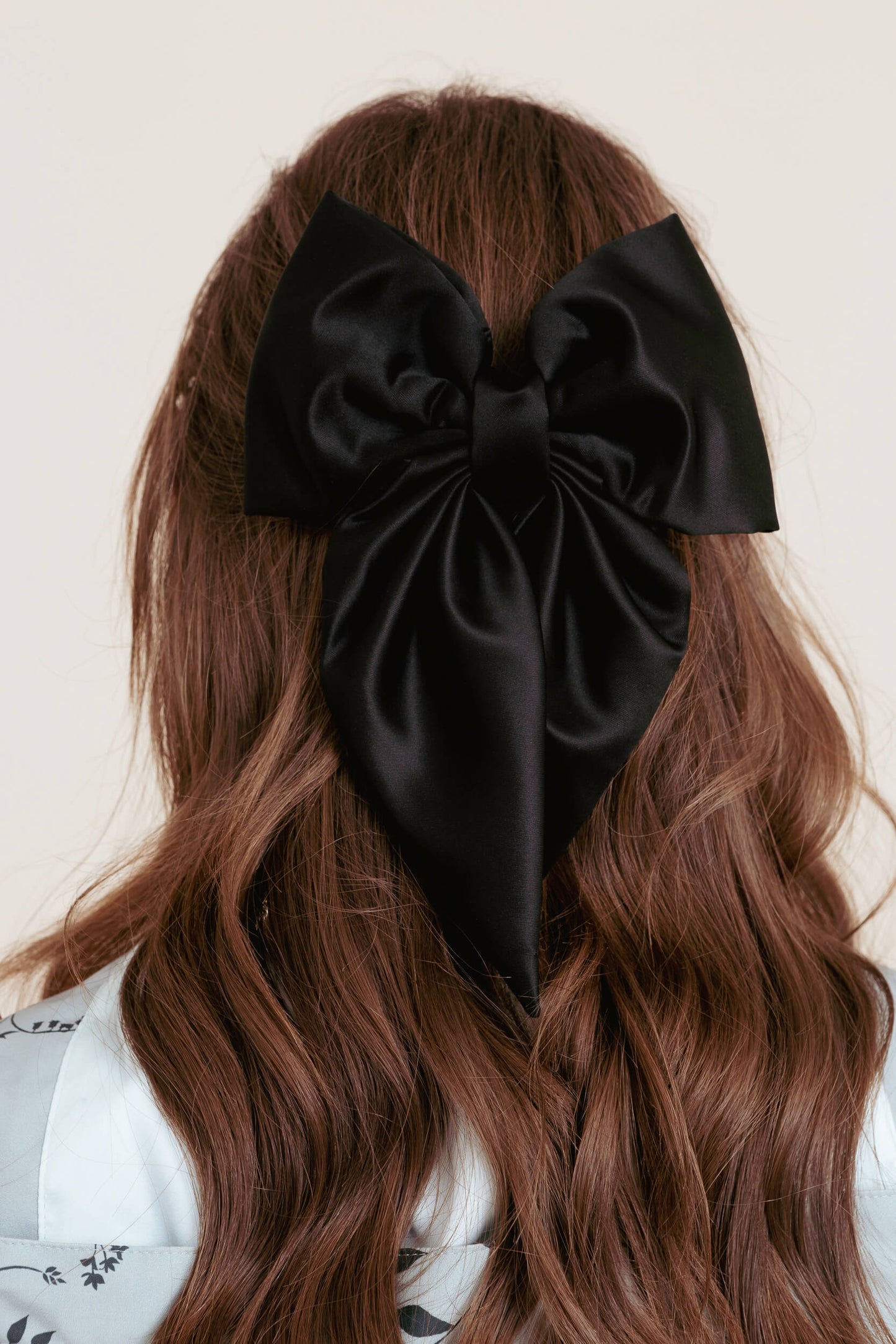 Black bow in hair against a neutral background