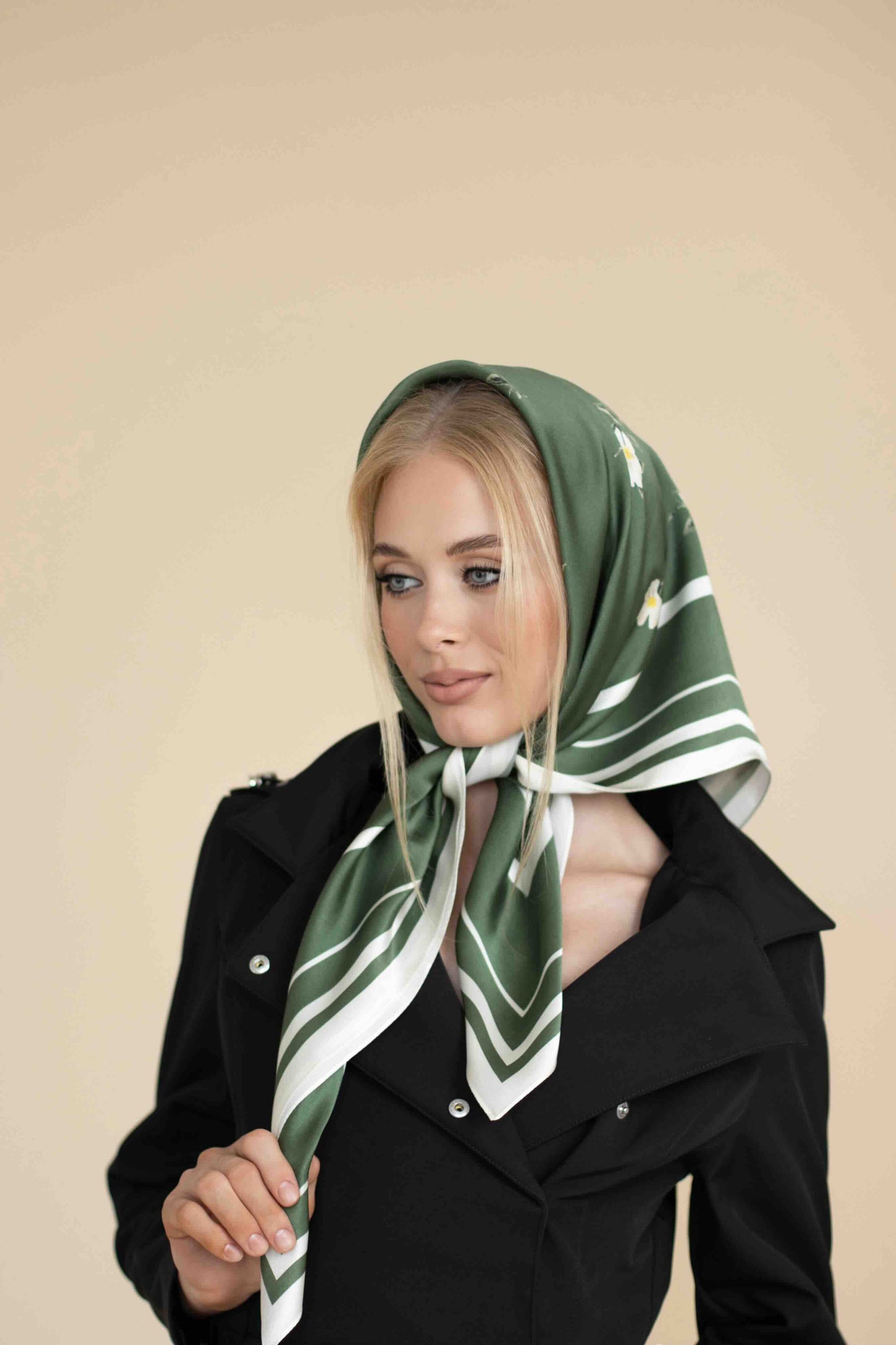 Woman wearing a green and white patterned scarf on a beige background