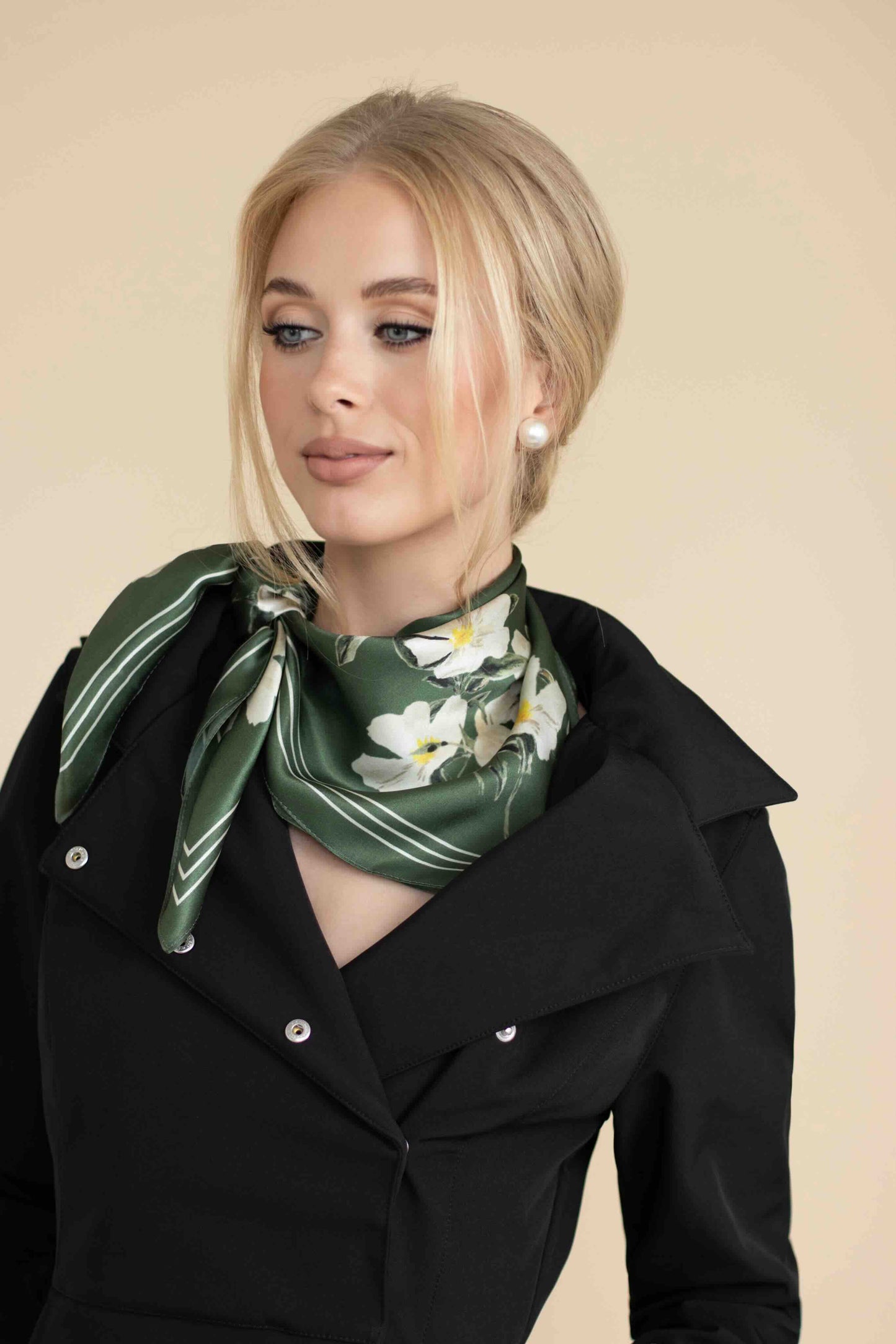 Woman wearing a green floral scarf on a beige background