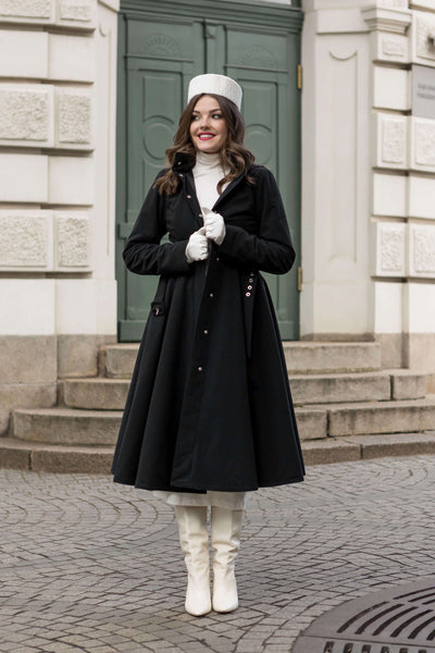 Black fitted winter coat with flared skirt and hidden pockets, combining warmth and elegance.