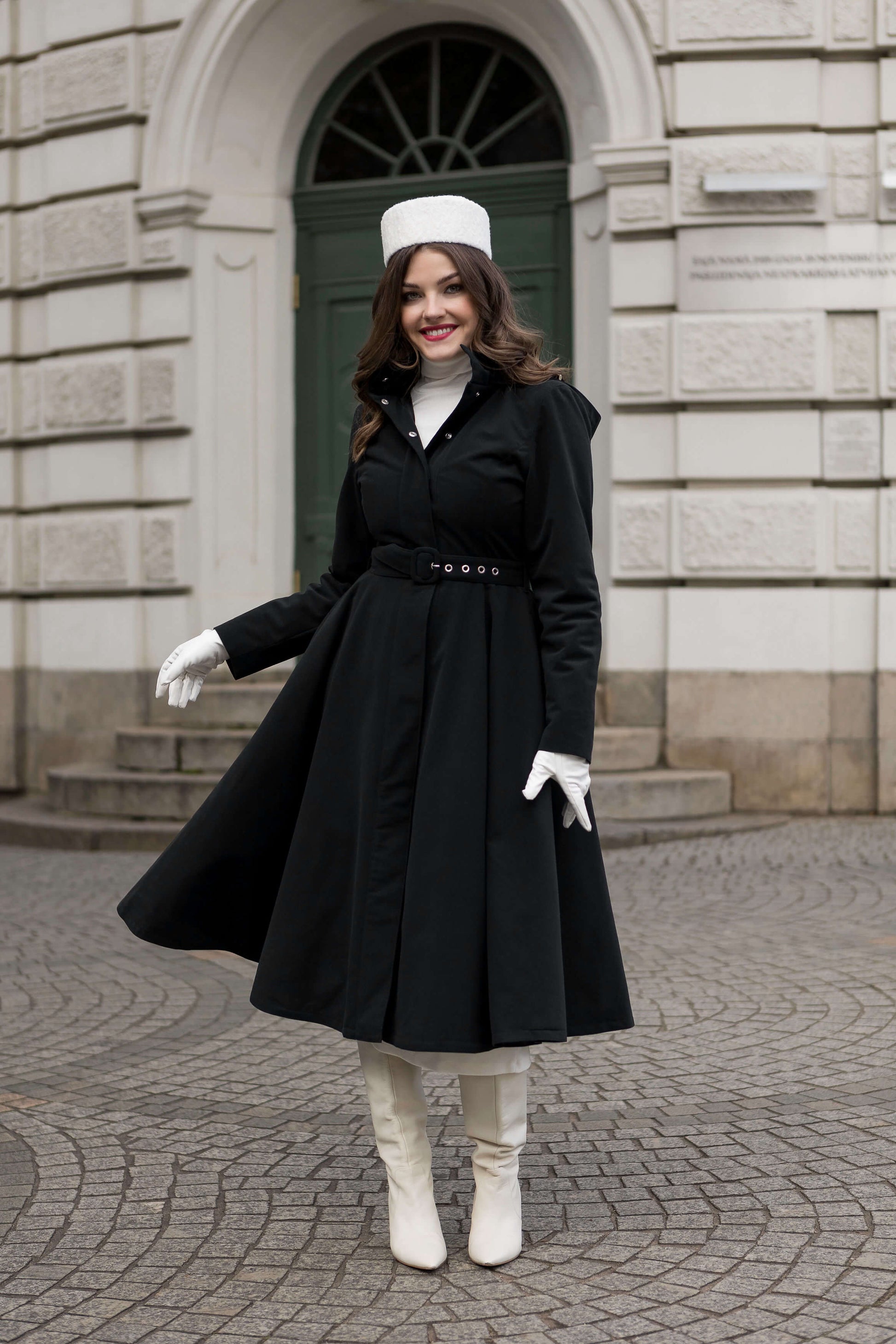 Woman wearing the Obsidian Frost midi black winter coat by RainSisters, styled with detachable hood and belt.