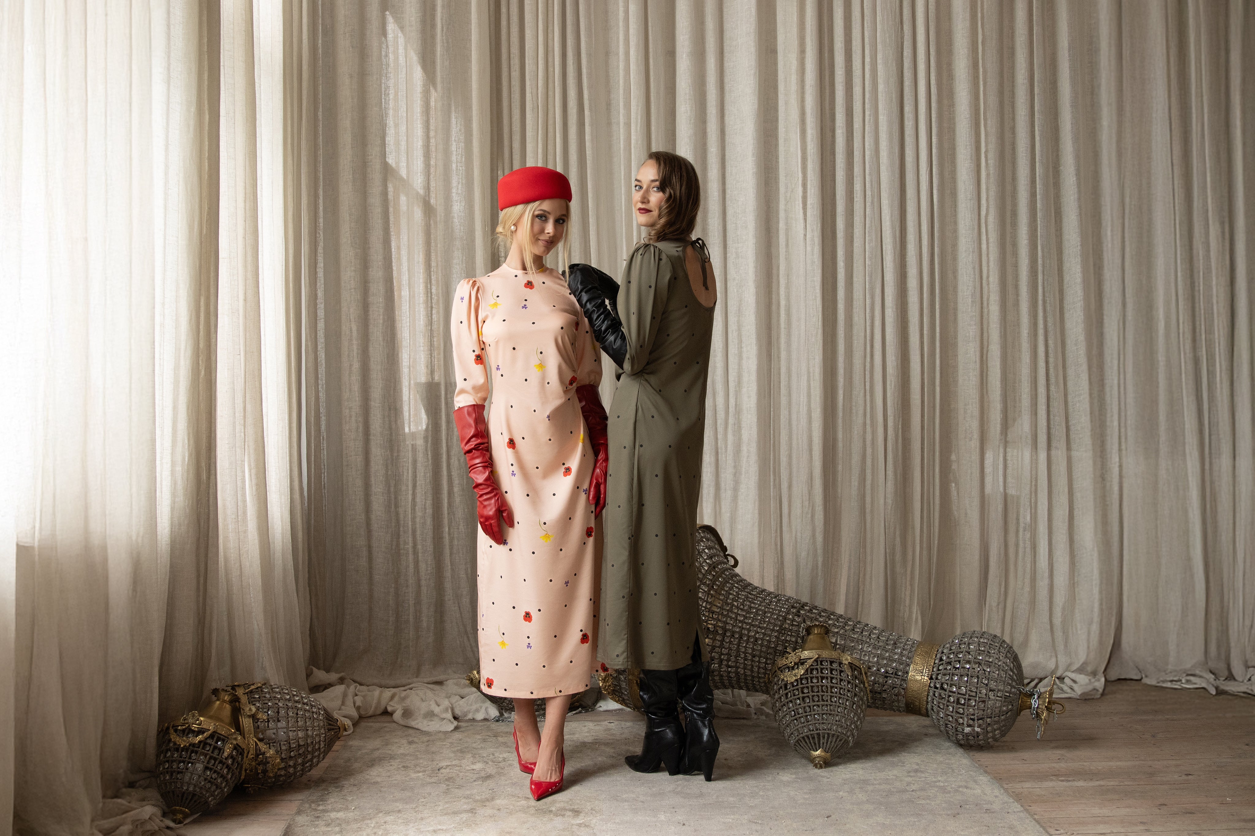 Two women in vintage clothing standing in a room with decorative elements.