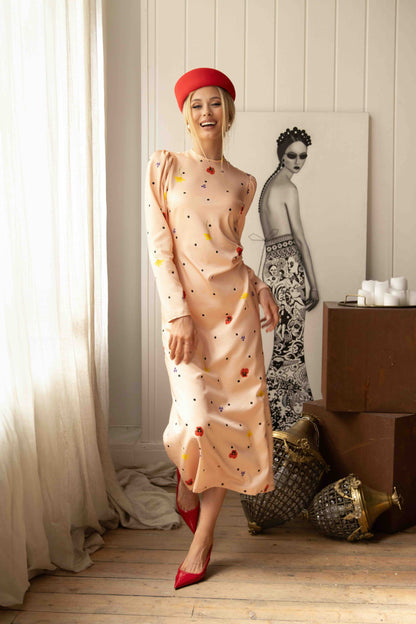 Romantic pink dress with floral and polka dot print, ribbon-tied back cutout and elegant flowing silhouette.