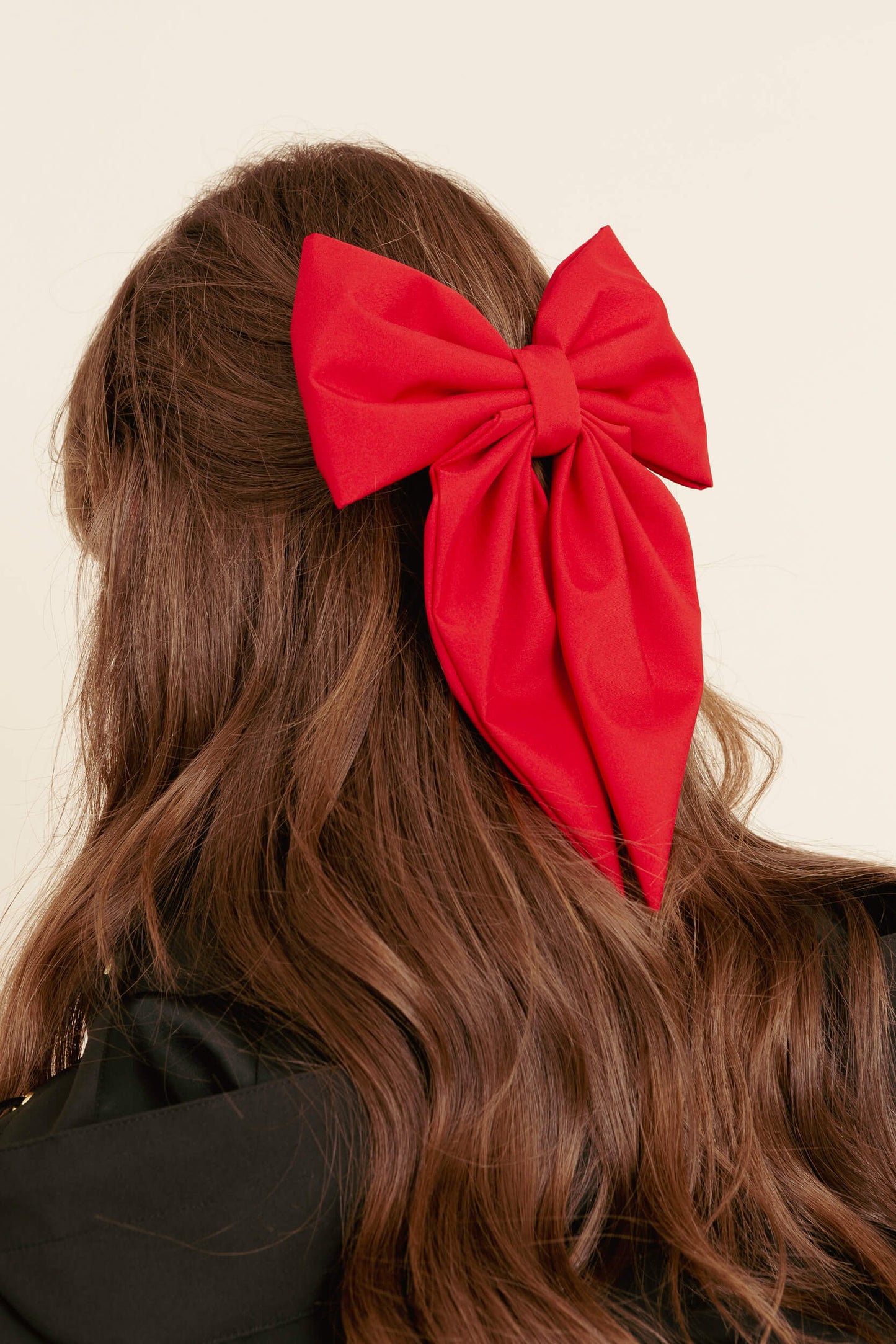 Red bow in a models hair against a neutral background