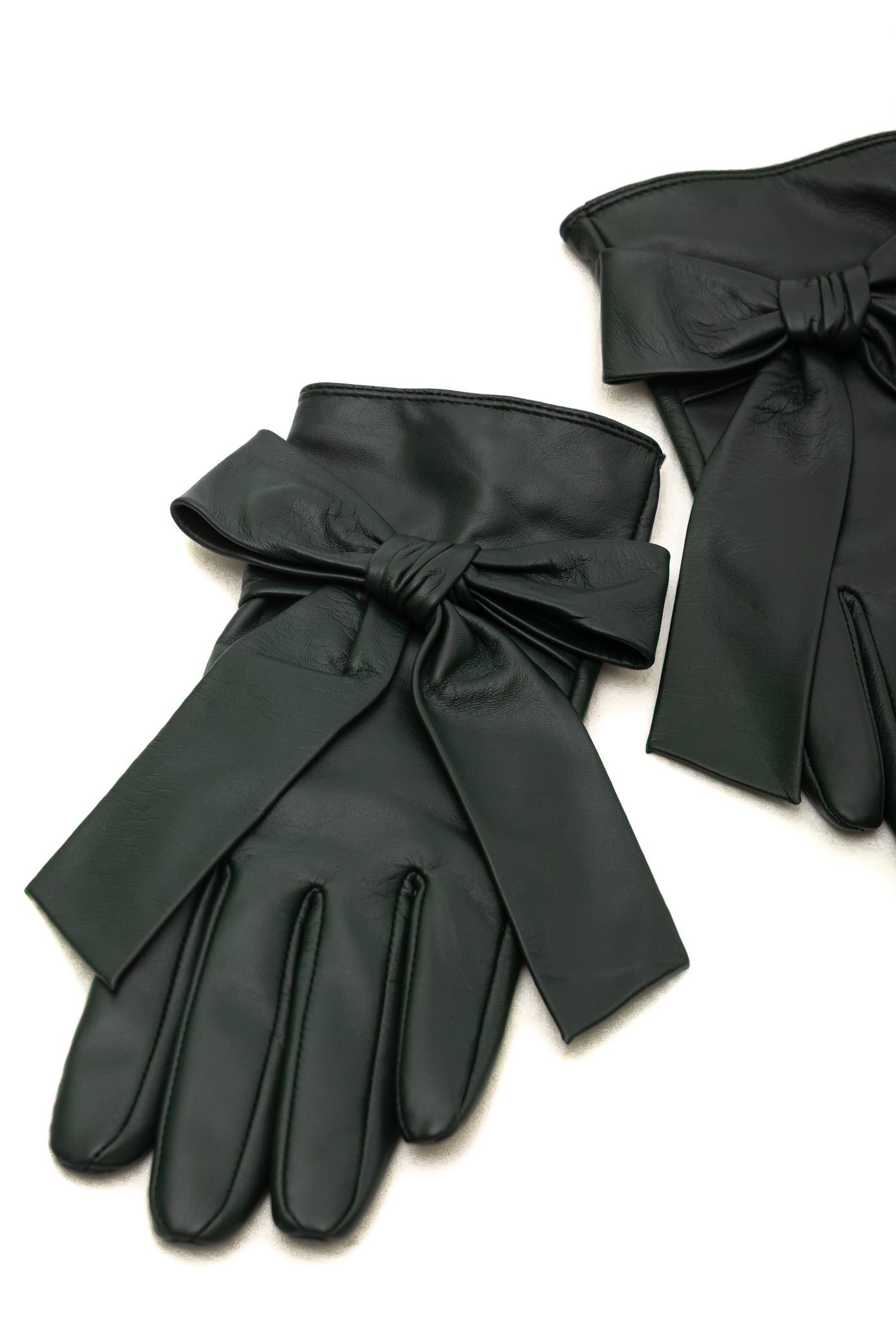 Dark green leather gloves with oversized bow details on the wrist, displayed on a clean white background.