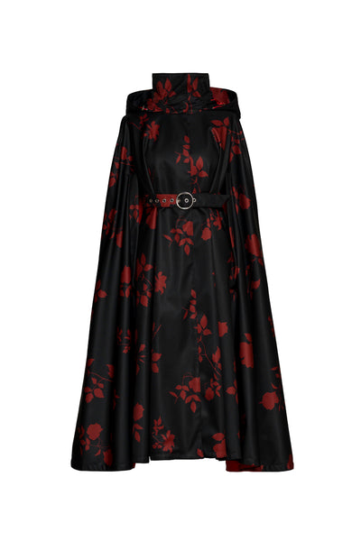 A black cape coat with red rose print by RainSisters featuring a high collar, a matching belt with a round silver buckle, and a flared skirt, shown against a plain white background.