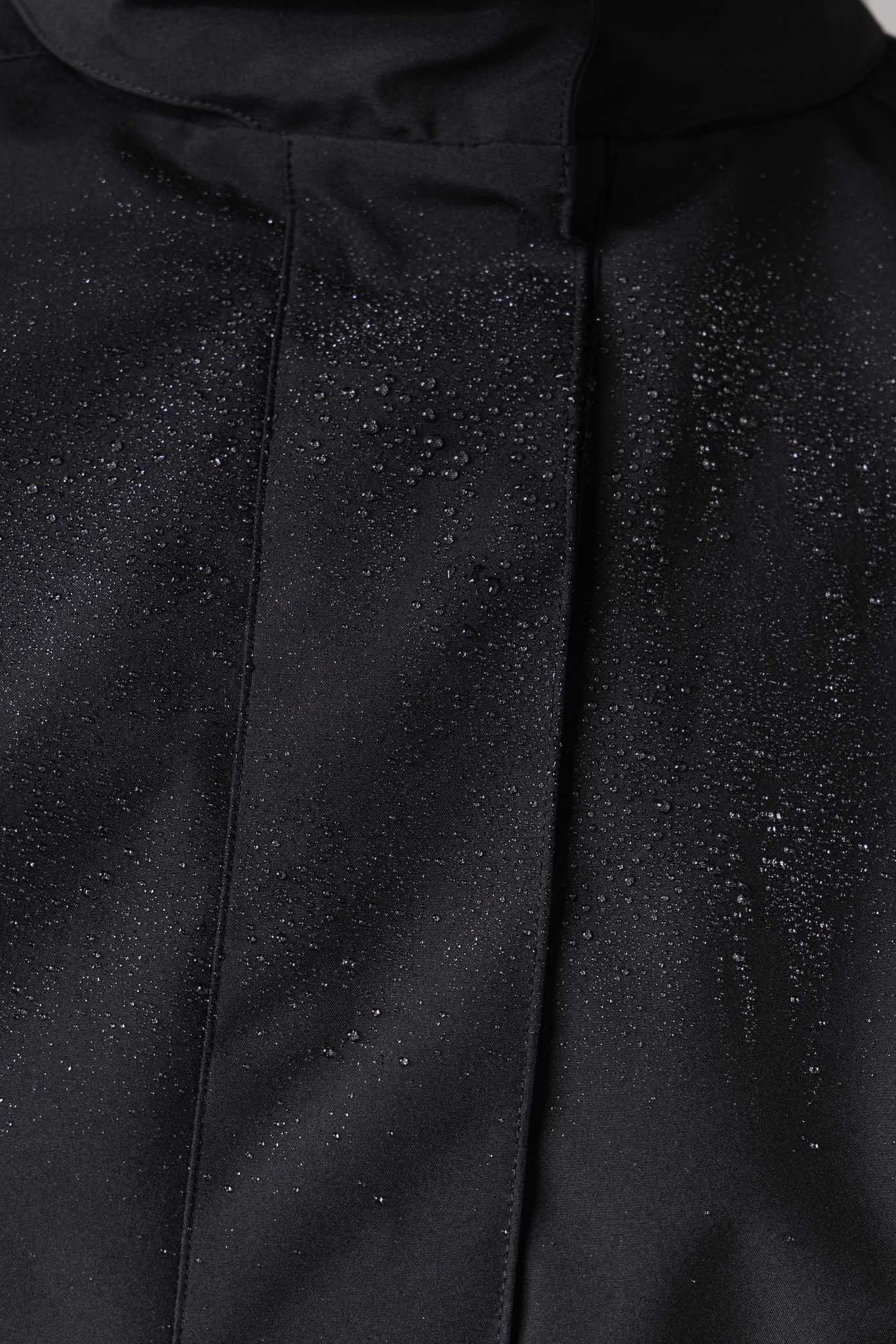 Close-up of light shell membrane fabric on black pleated women's waterproof trench coat