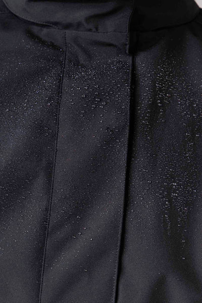 Close-up of light shell membrane fabric on black pleated women's waterproof trench coat