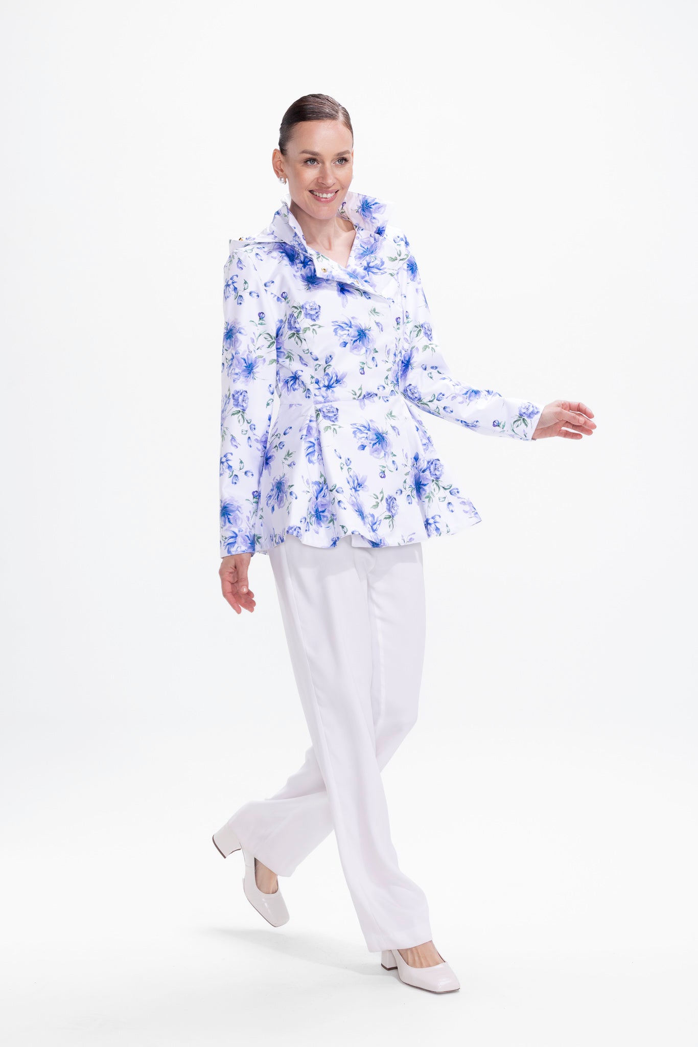 Model in motion wearing white water-resistant jacket with blue floral print and tailored silhouette