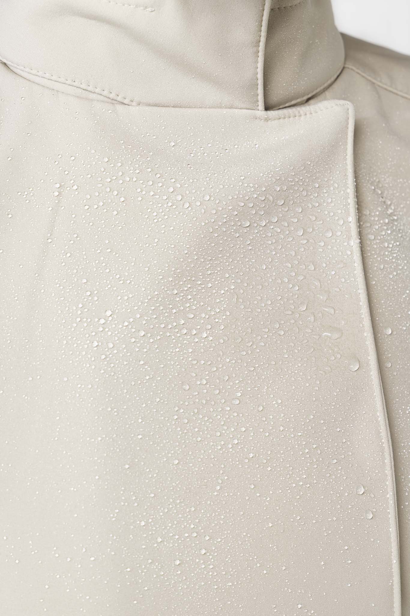 Close-up of beige waterproof outerwear fabric on women's designer trench coat