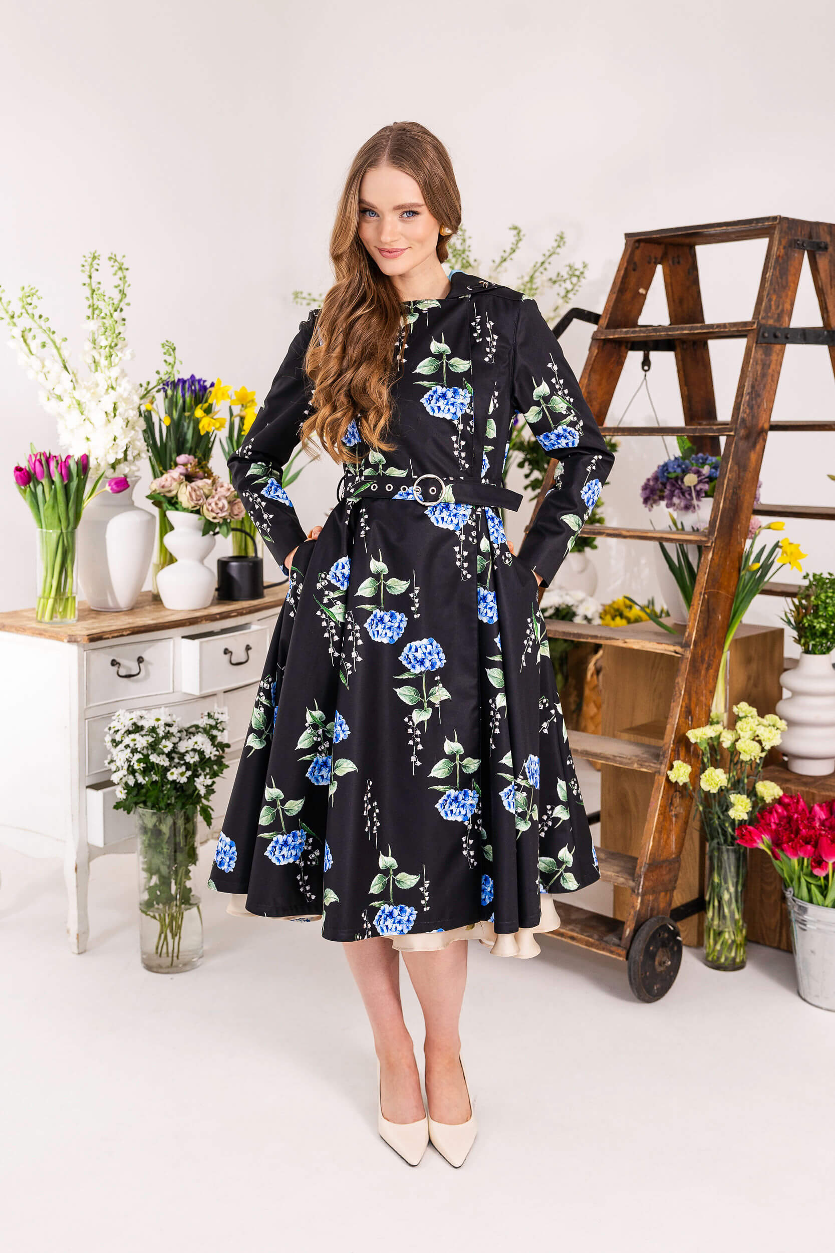 Black double-breasted floral coat with lily of the valley print and belt.