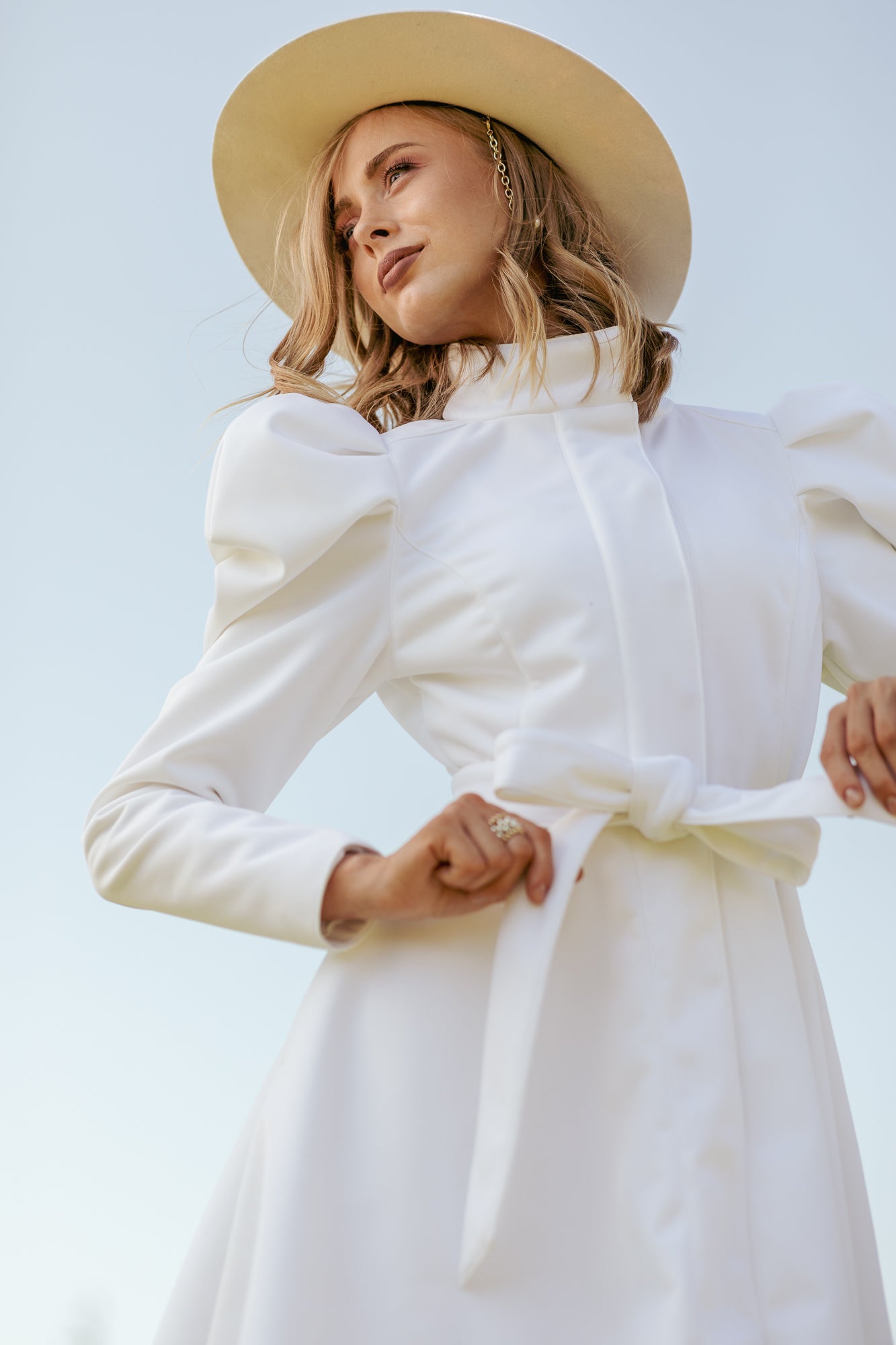 White fit and flare coat with balloon sleeves worn as romantic bridal and reception outerwear